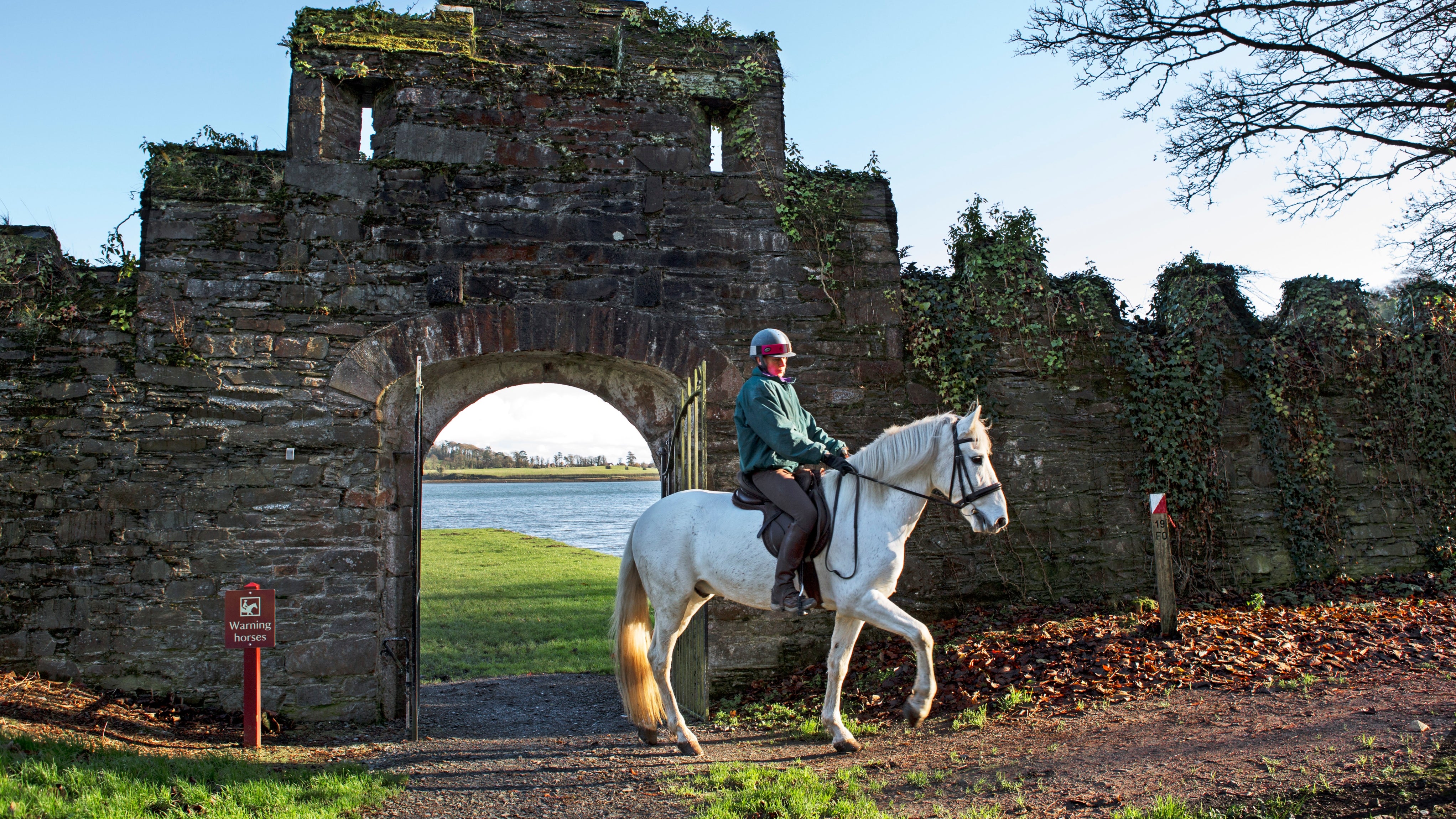 A horse and rider coming through a stone archway at Castle Ward.