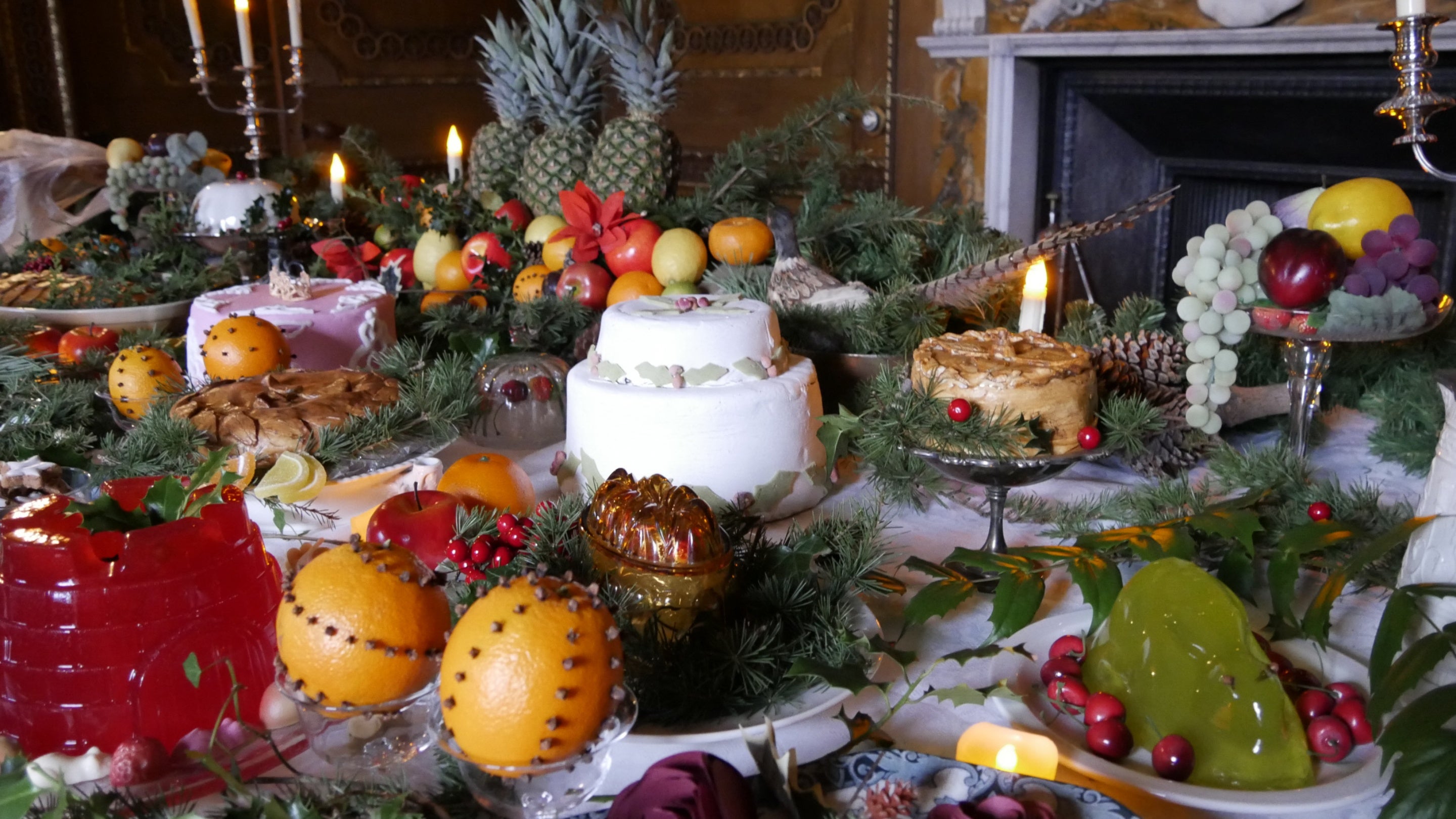 Table laid with traditional Christmas food, with silver platters interspersed with spruce branches