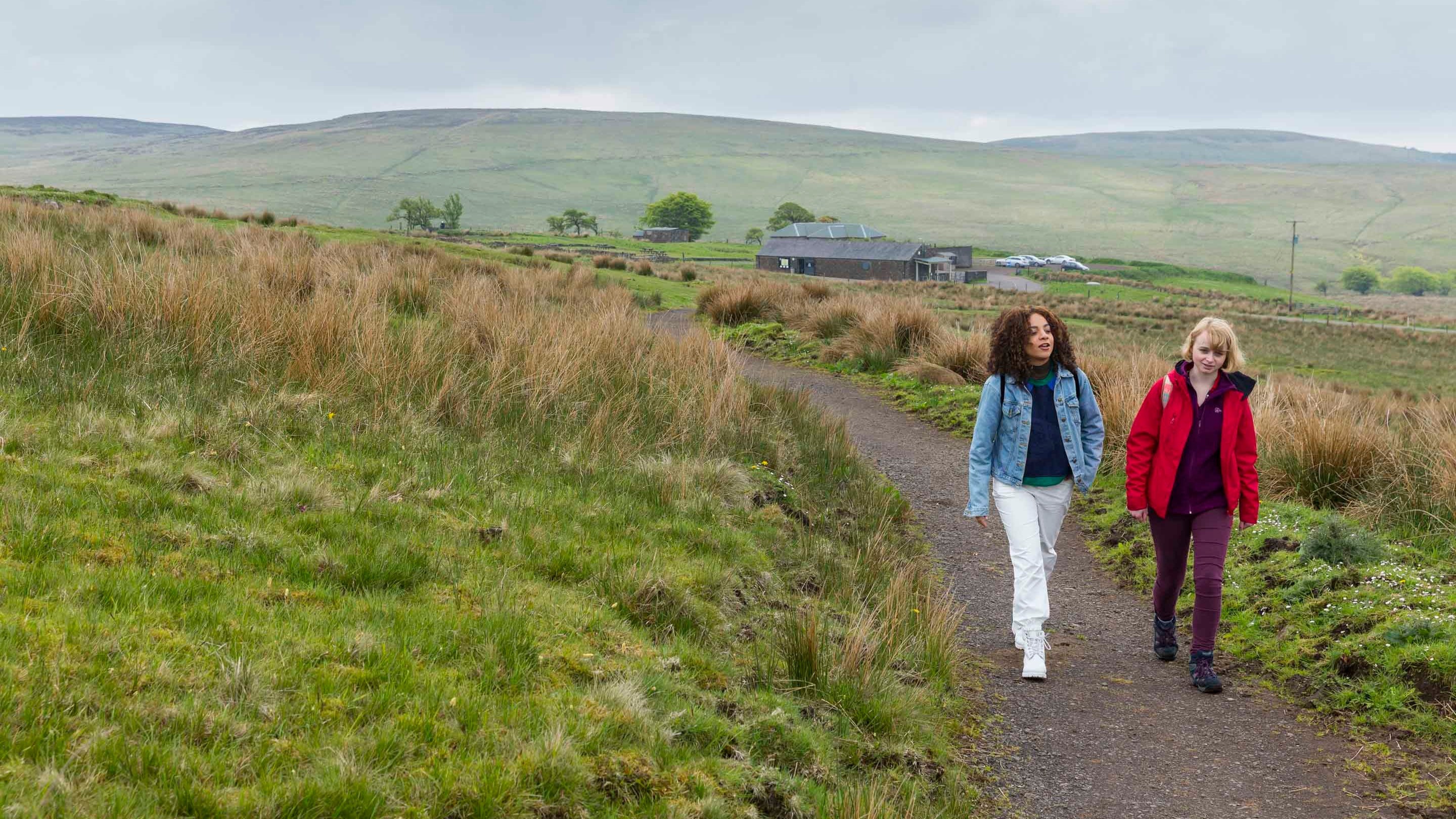Two visitors walking along a footpath at Divis and the Black Mountain, with countryside visible all around them