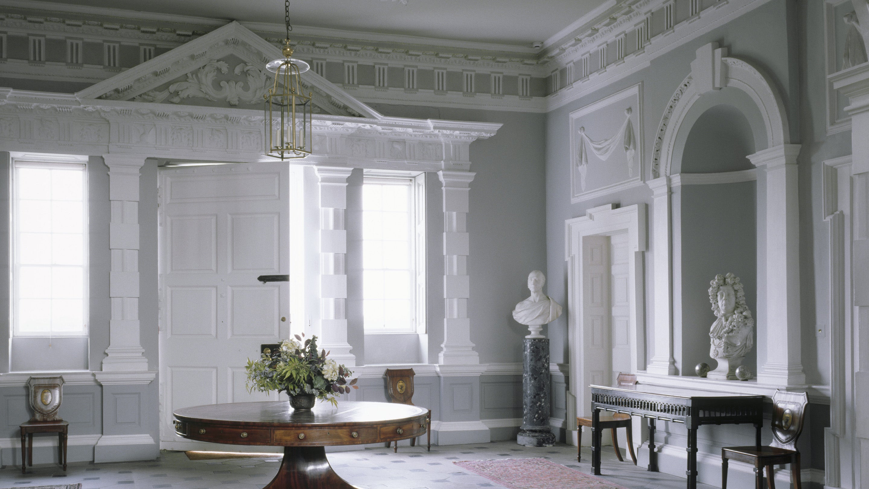 The Entrance Hall at Florence Court looking towards the door with its tripartite doorcase. An entablature with a frieze of triglyphs runs around the hall with rusticated Doric pillars.