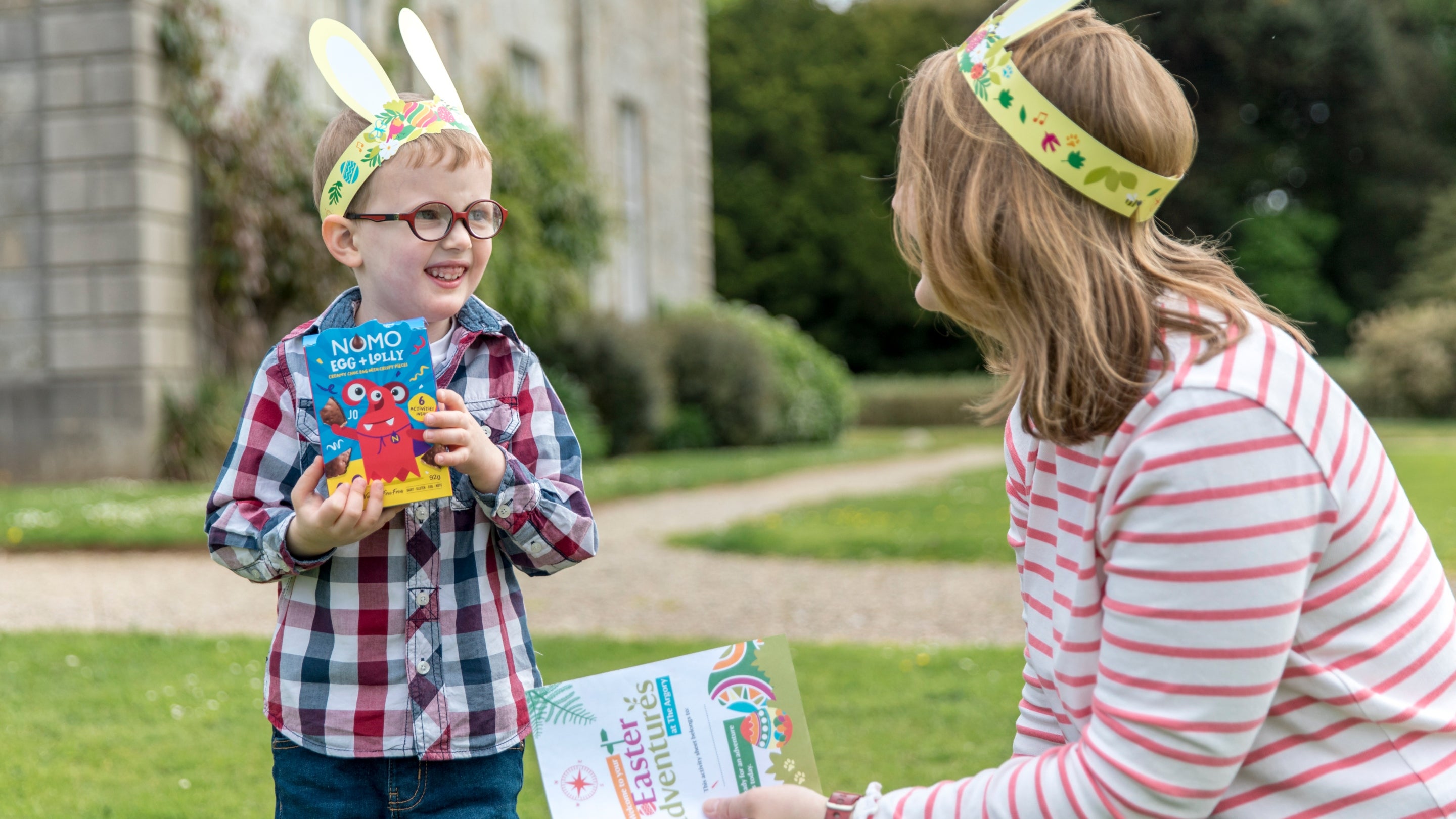 A young boy holding an Easter egg beside his mum on a sunny day in Fermanagh