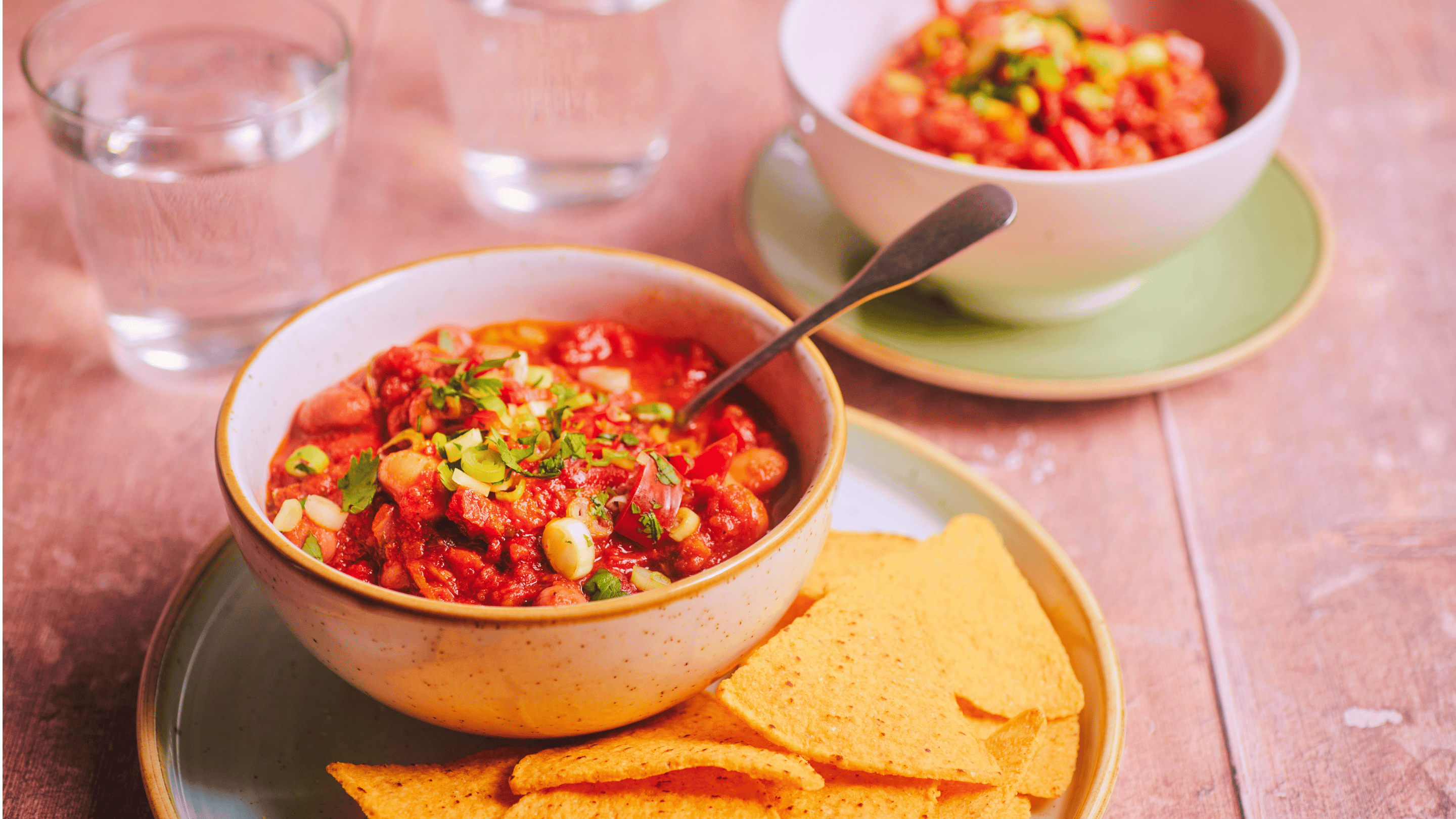 Bowl of mixed bean chilli topped with spring onions and fresh herbs, served with tortilla chips on a place in the Giant's Causeway Visitor Centre Café