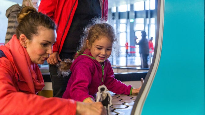 Family in the Giant's Causeway Visitor Centre, exploring the interactive exhibition and interpretation area