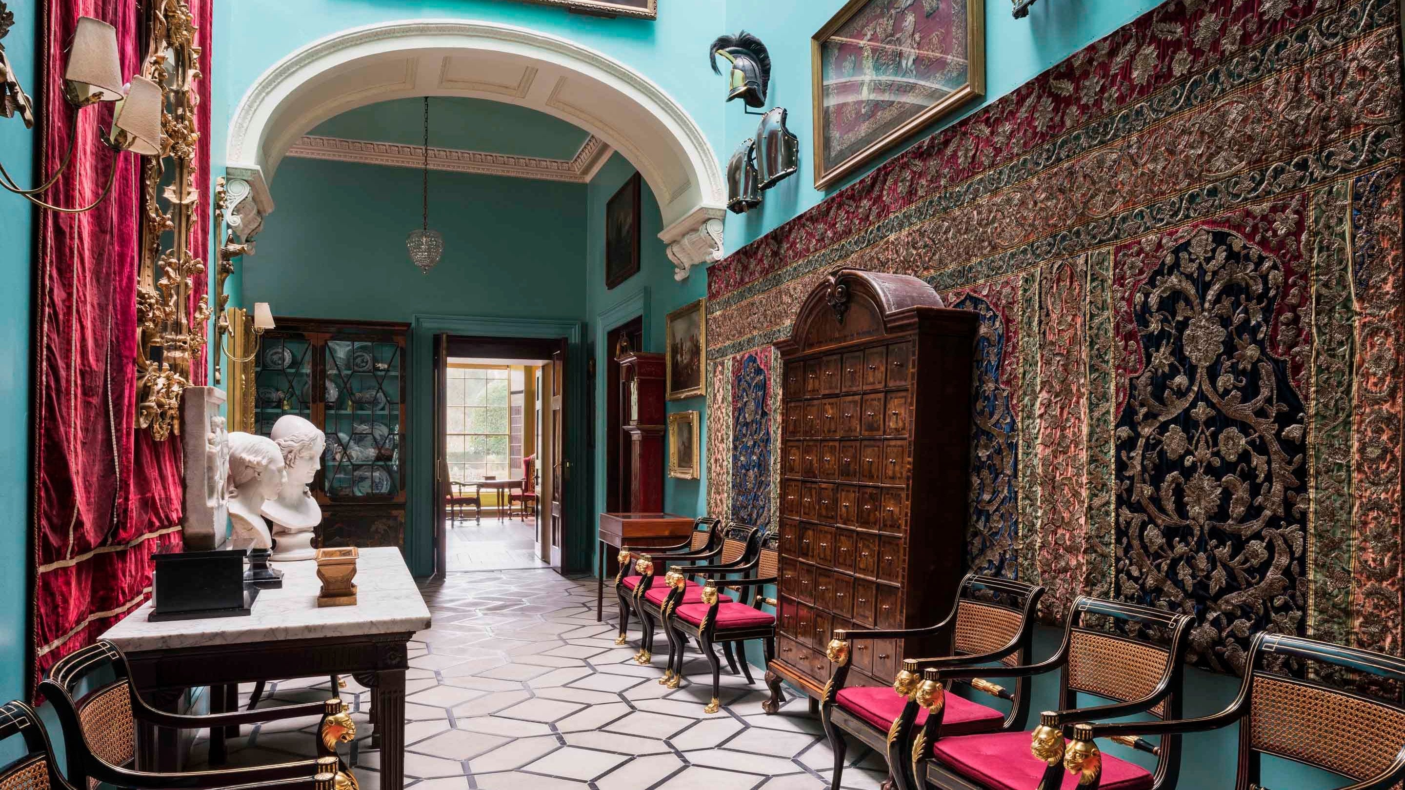 The Black and White Stone Hall at Mount Stewart, where armour is displayed along the walls and a marble sculpture of Helen of Troy can be seen