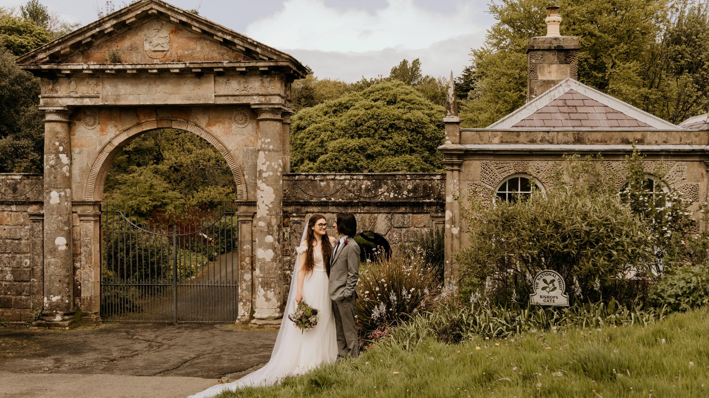 An image of a bride and groom standing outside the Bishop's Gate entrance to Downhill Demesne.