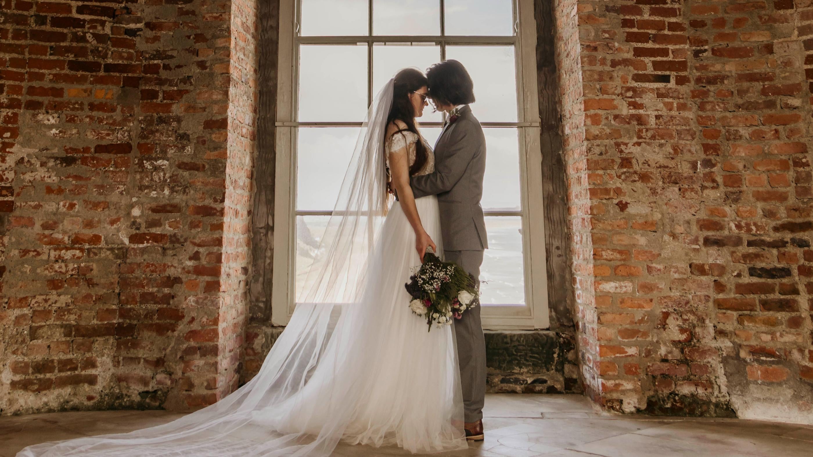 A bride and groom standing in front of the tall windows at Mussenden Temple.