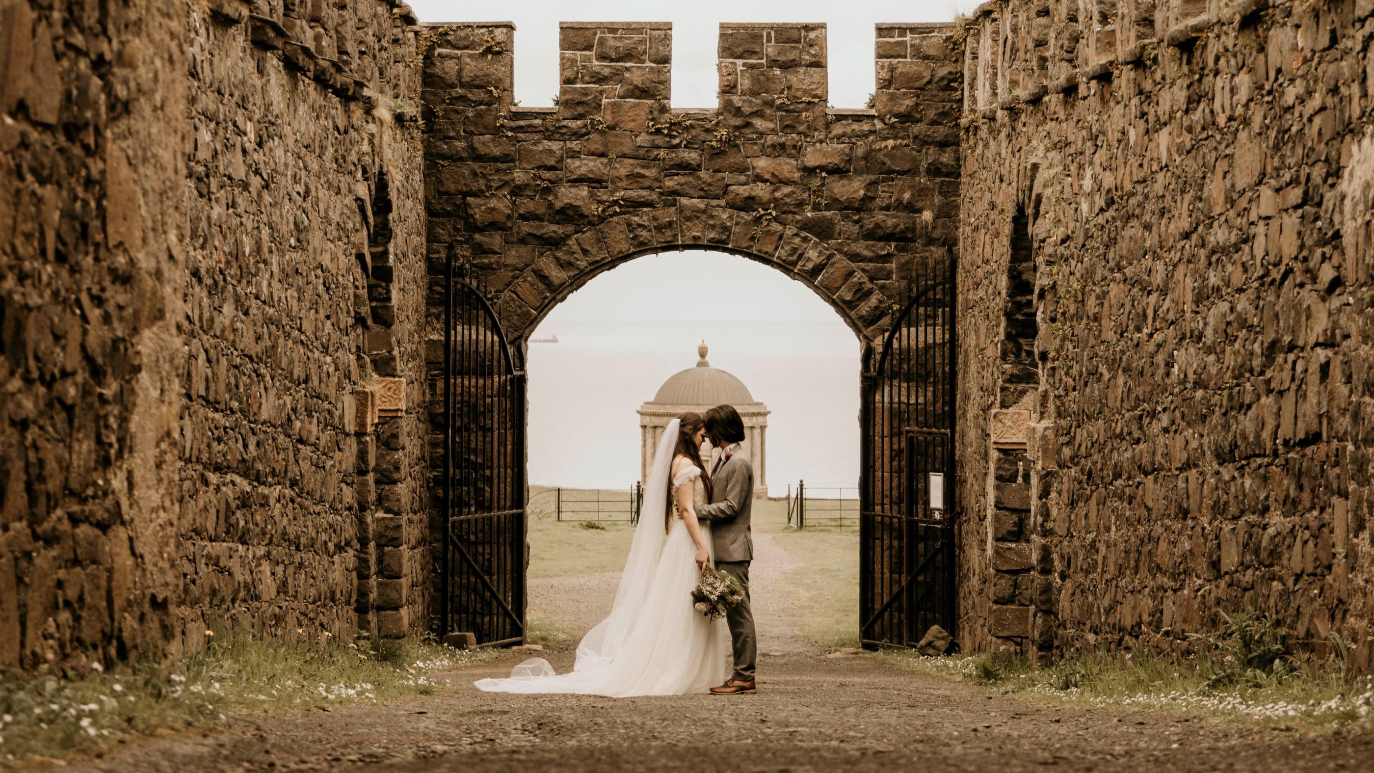 An image of a bride and groom standing in the ruins of Downhill House.