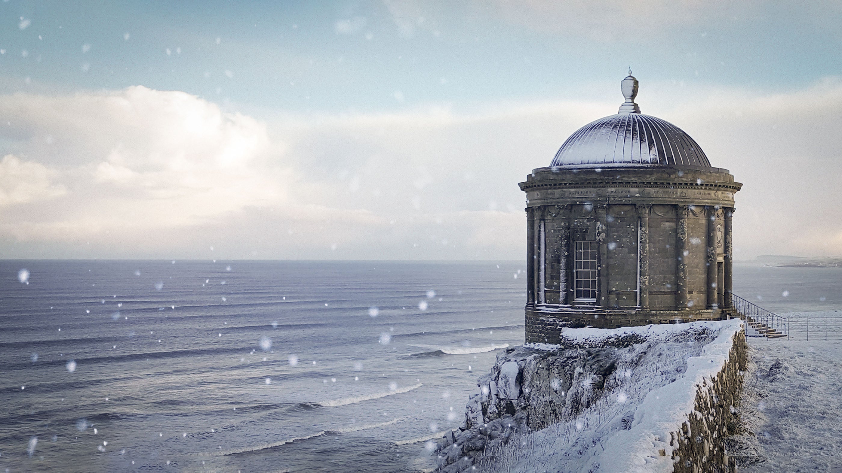 High above the crashing Atlantic waves, the iconic Mussenden Temple stands on the edge of the snow-covered cliffs of Downhill Demesne.