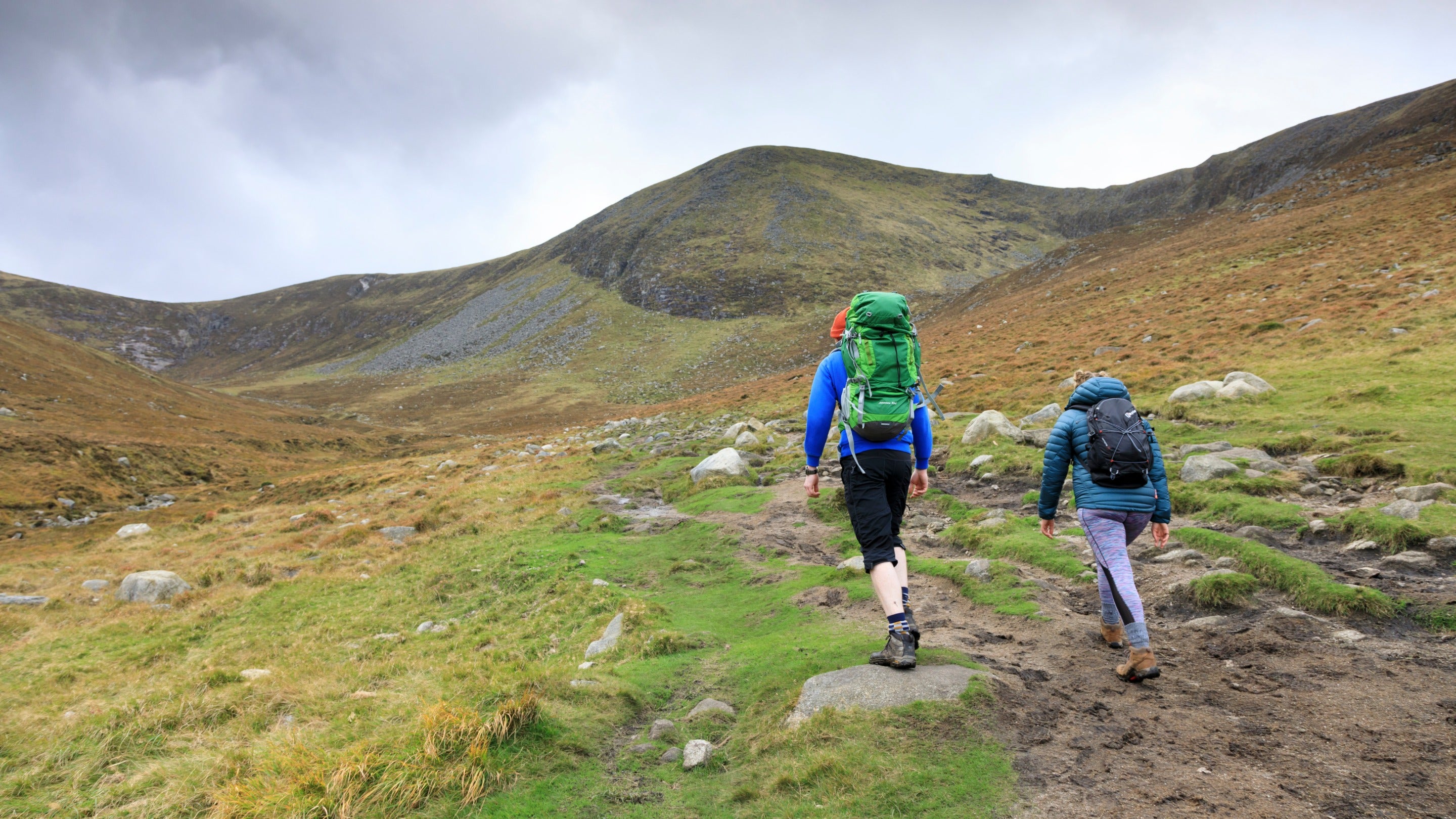 Walkers approaching a braided path showing erosion across a wide area on the way towards the summit of Slieve Donard in the Mourne Mountains, County Down