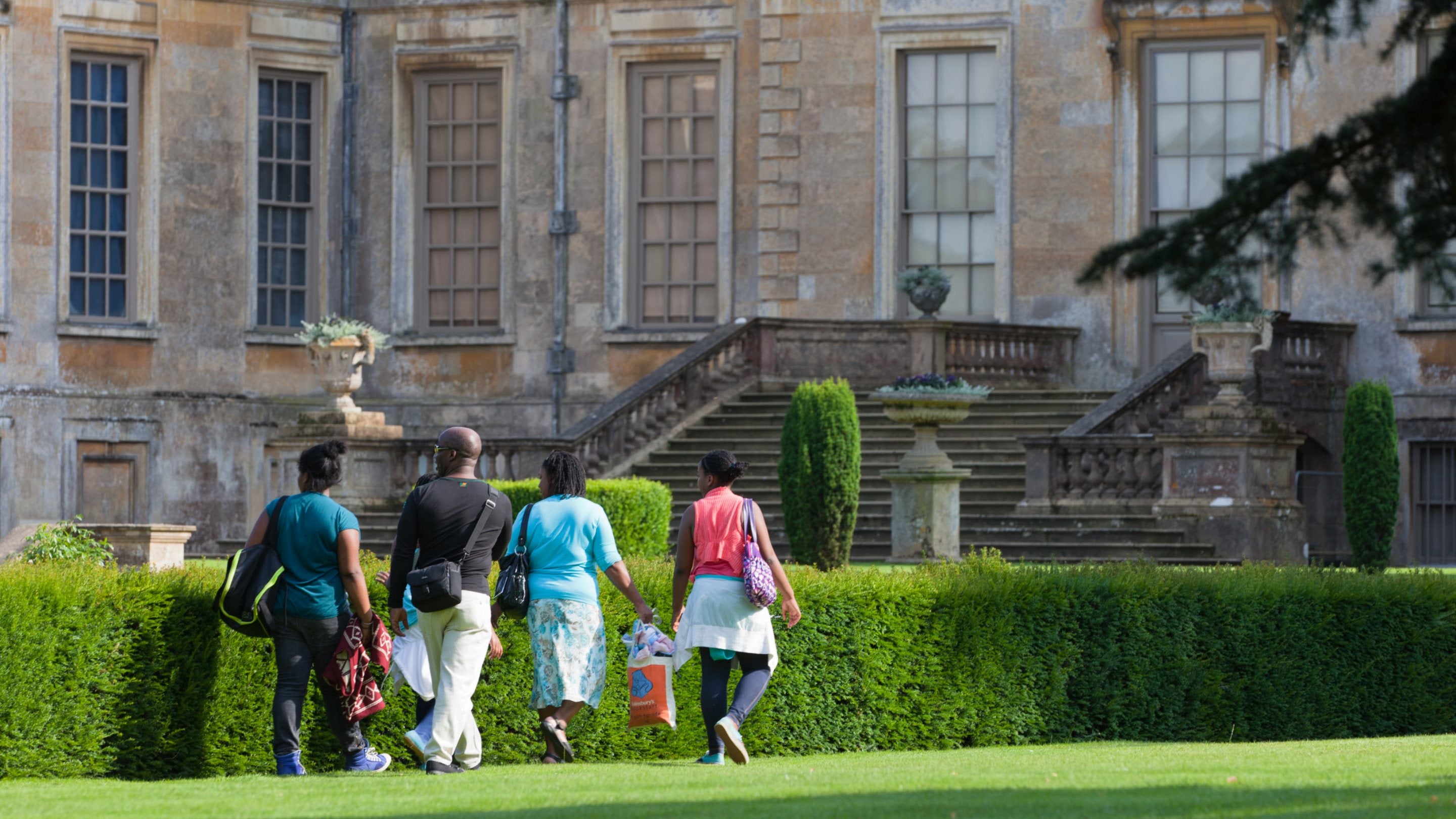 Visitors in the garden to the side of the house at Belton House, Lincolnshire.