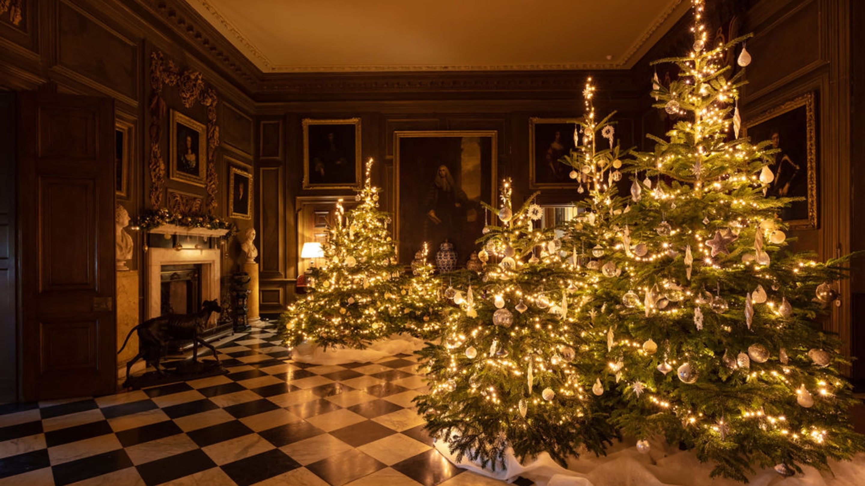 Marble Hall at Belton decorated for Christmas, transformed into a winter wonderland with multiple snowy trees.