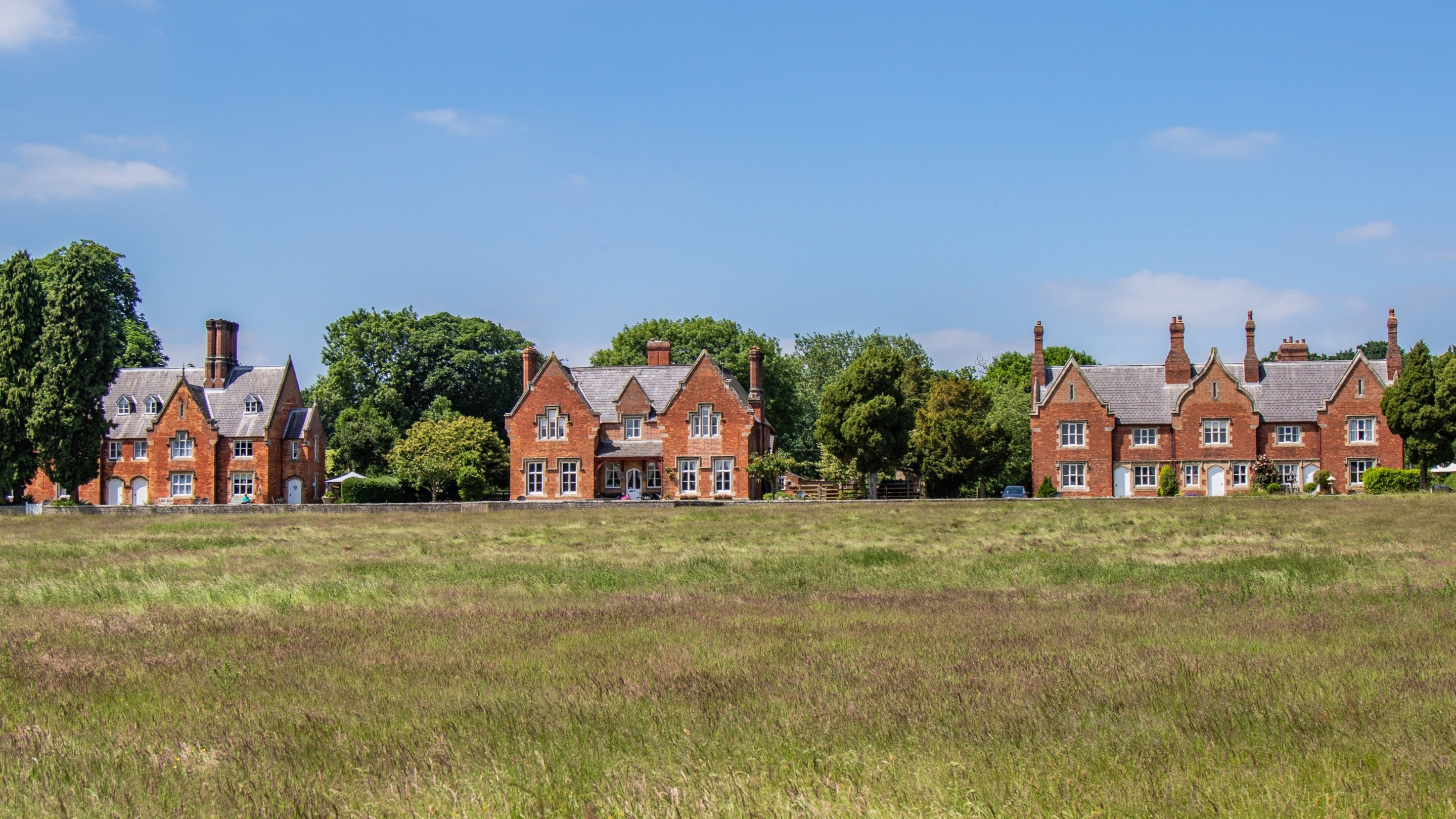 Looking across a green field towards a row of brick houses in Hardwick village