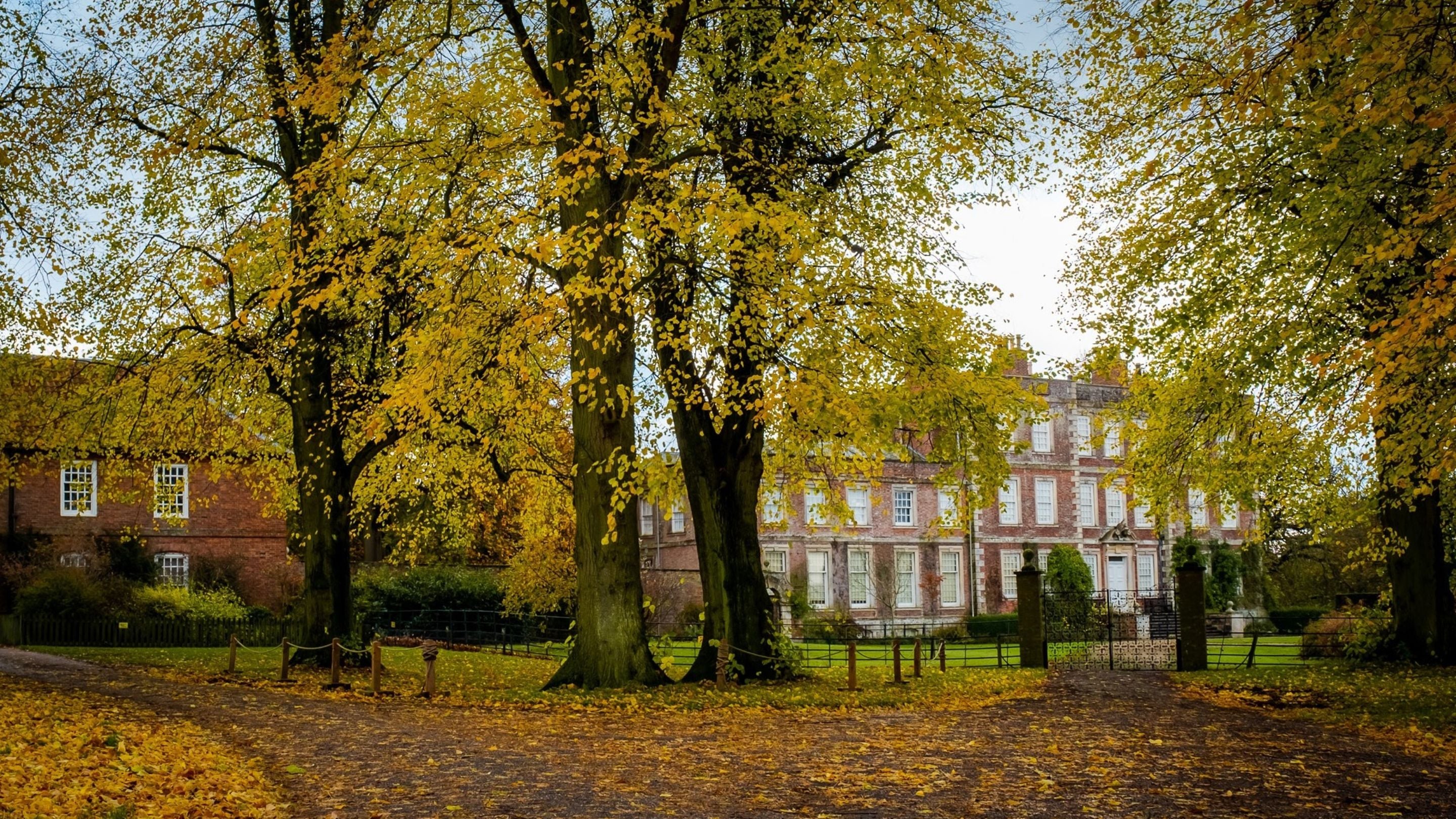 Gunby Hall in Autumn, surrounded by yellow and orange leaves.