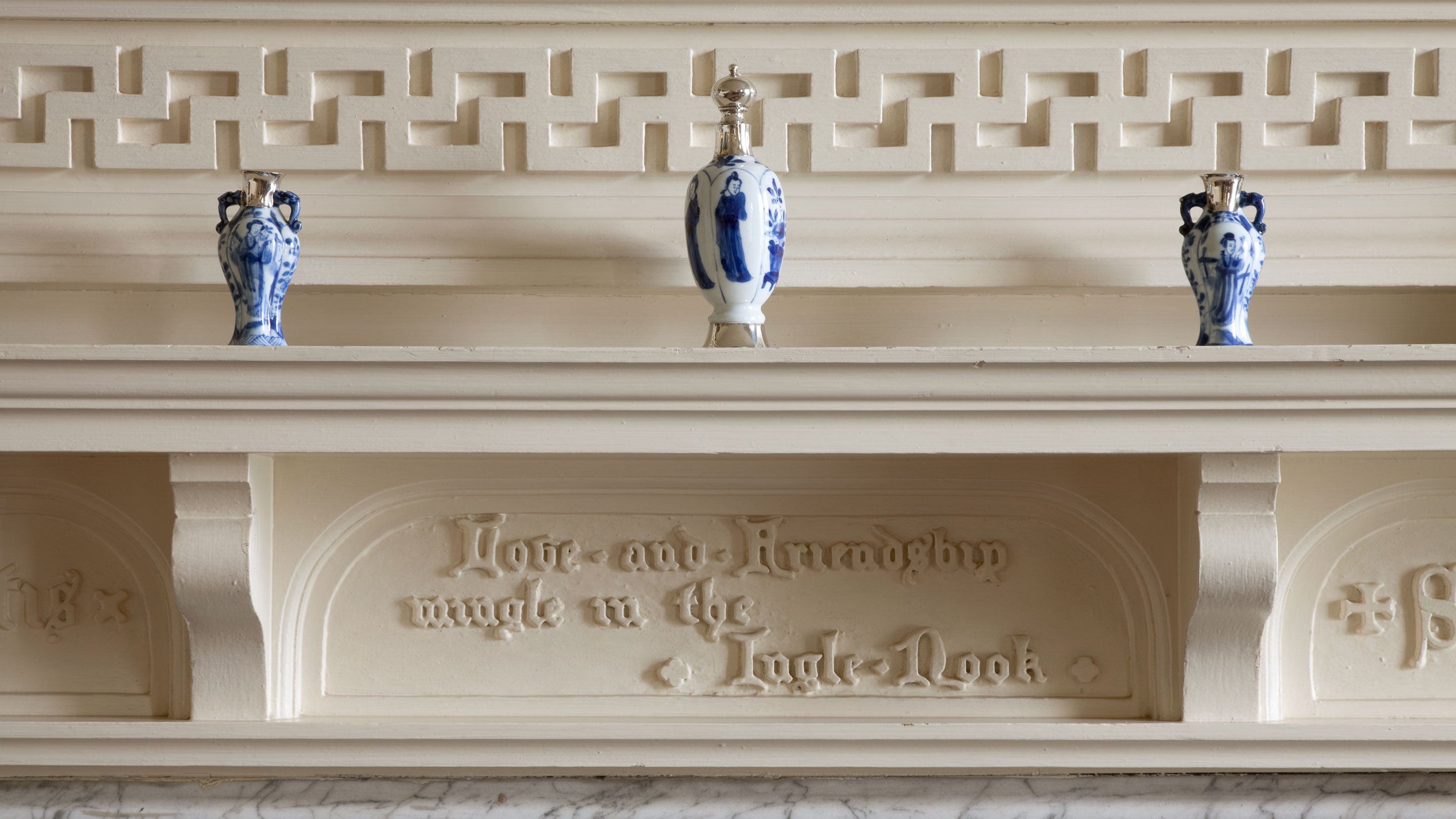 The fire surround in the Dining Room at Gunby Hall, Lincolnshire, set with three blue and white vases on the mantelpiece and inscribed 'Love and Friendship mingle in the Ingle-Nook' underneath,