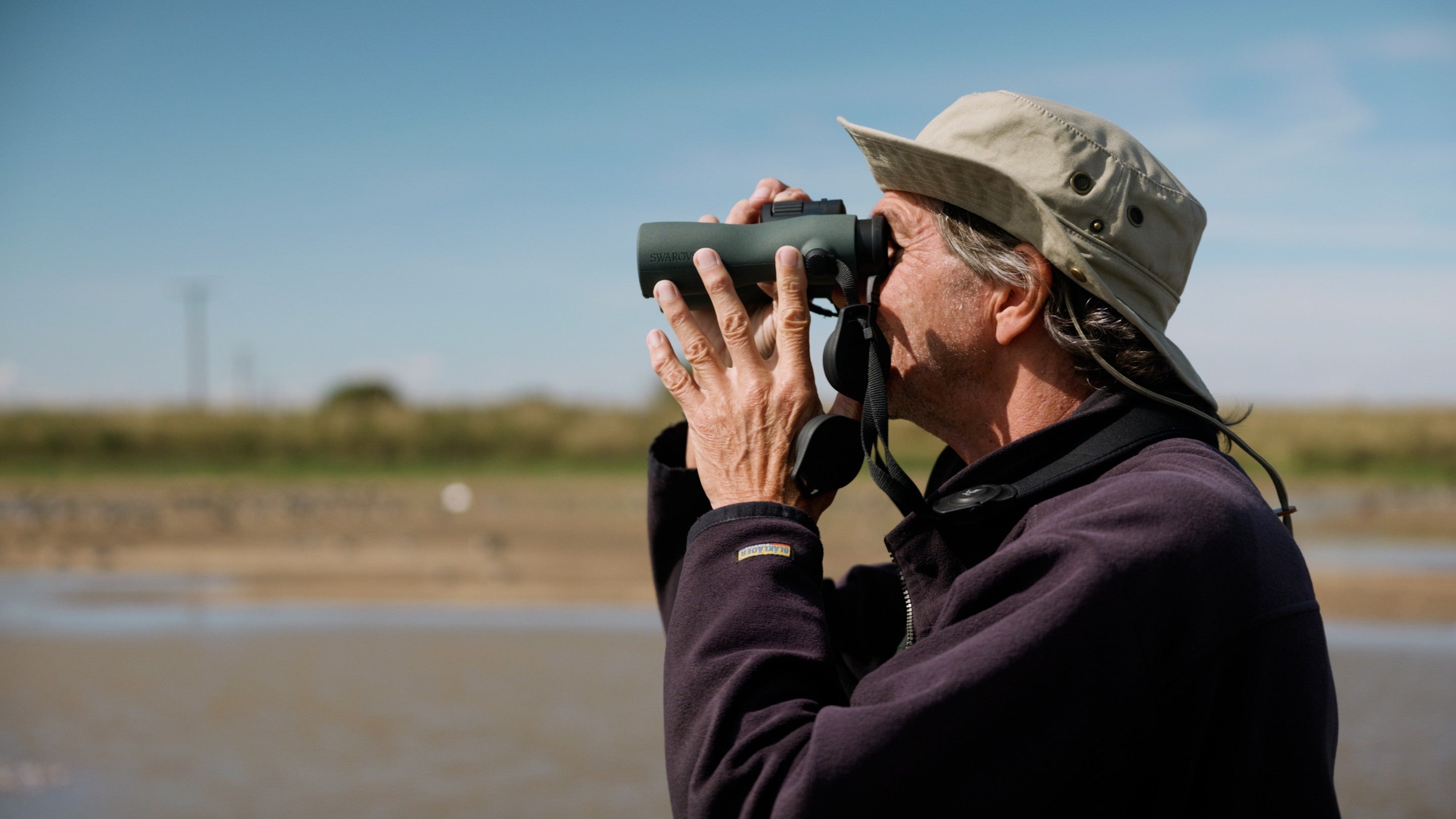 A man looking through binoculars at Sandilands nature reserve.