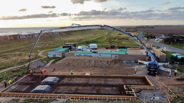 Concrete foundations being poured for the new café building at Sandilands, with construction team and equipment on site near the coast.