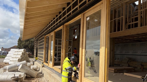 Workers installing wooden-framed windows and doors into the new café building at Sandilands Nature Reserve.