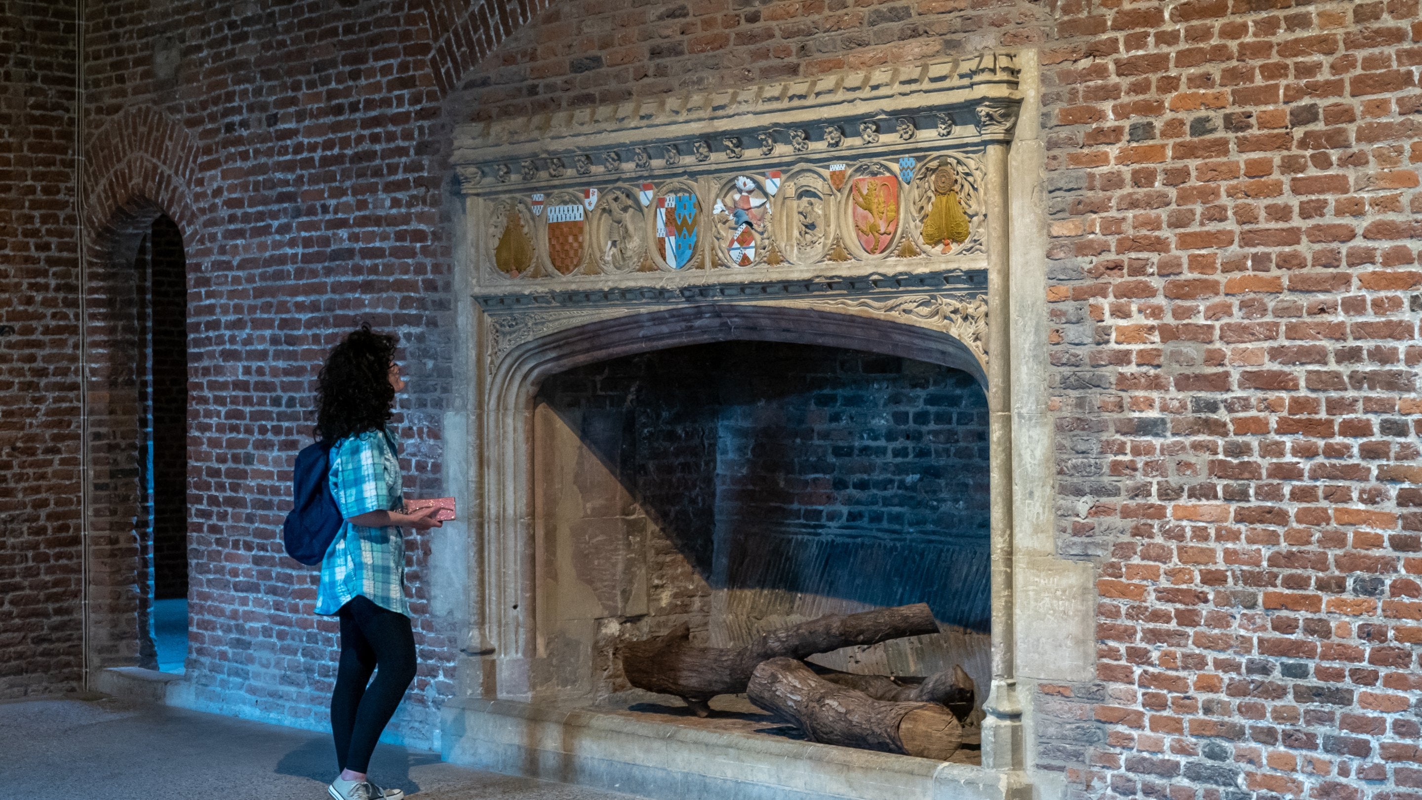 A woman looking at a fireplace inside Tattershall Castle.