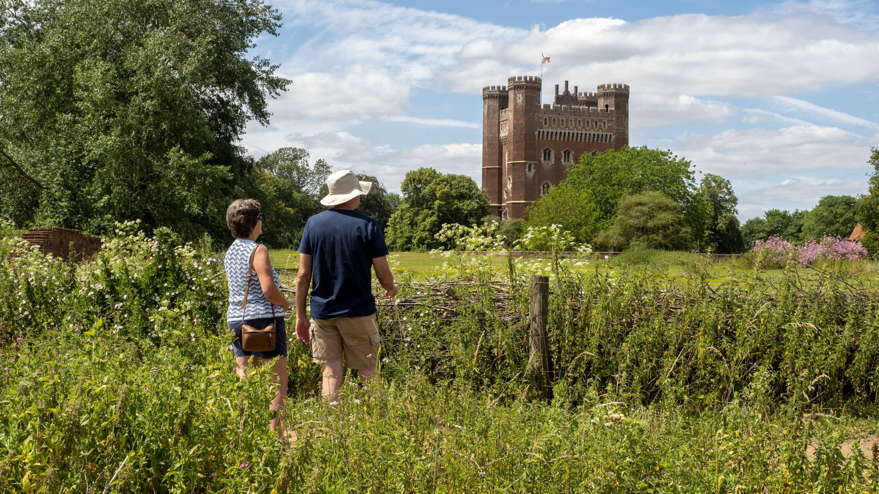 A man and a woman looking across the fields at Tattershall Castle.