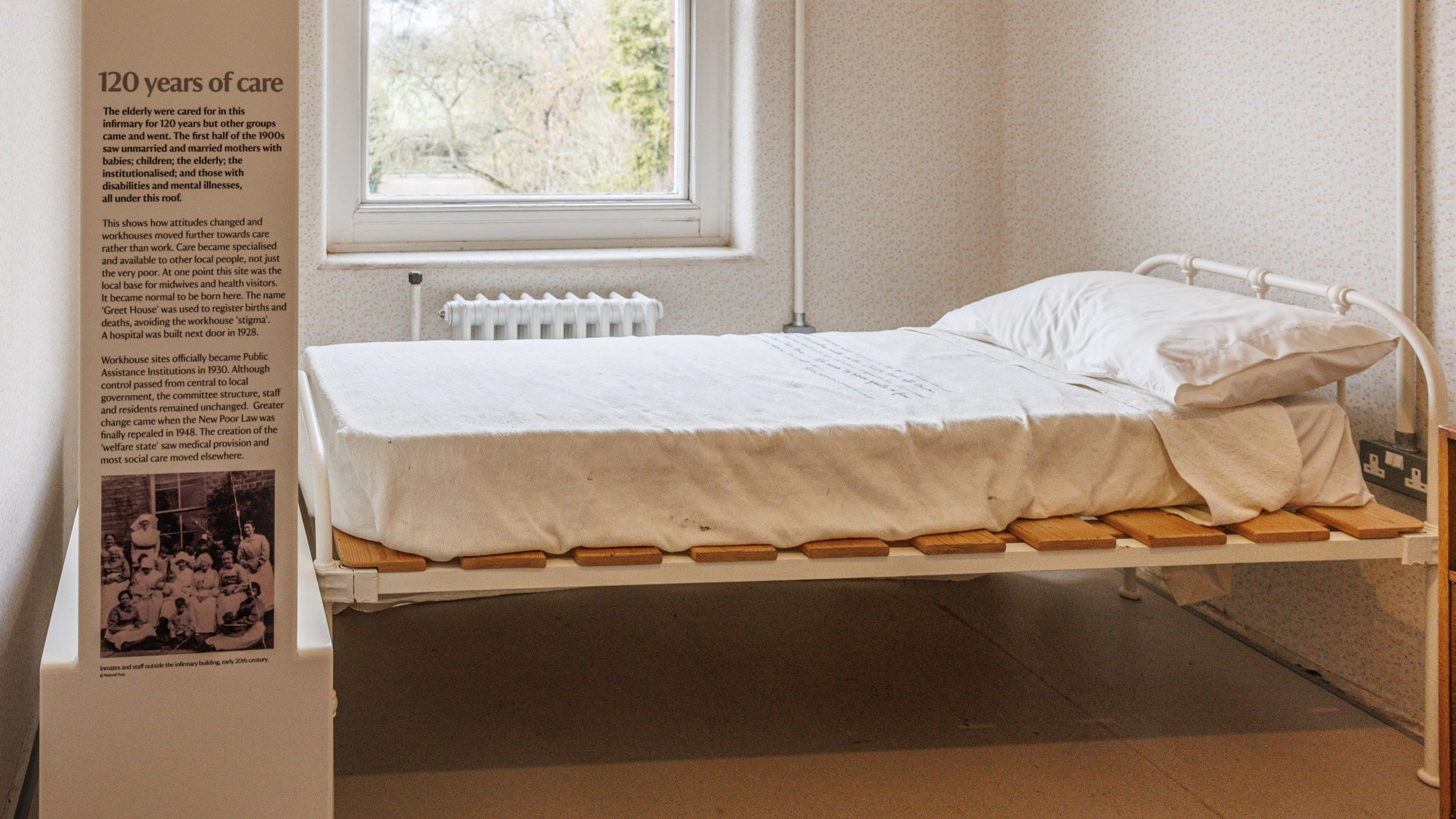 A bed in the Infirmary with an information board to the left