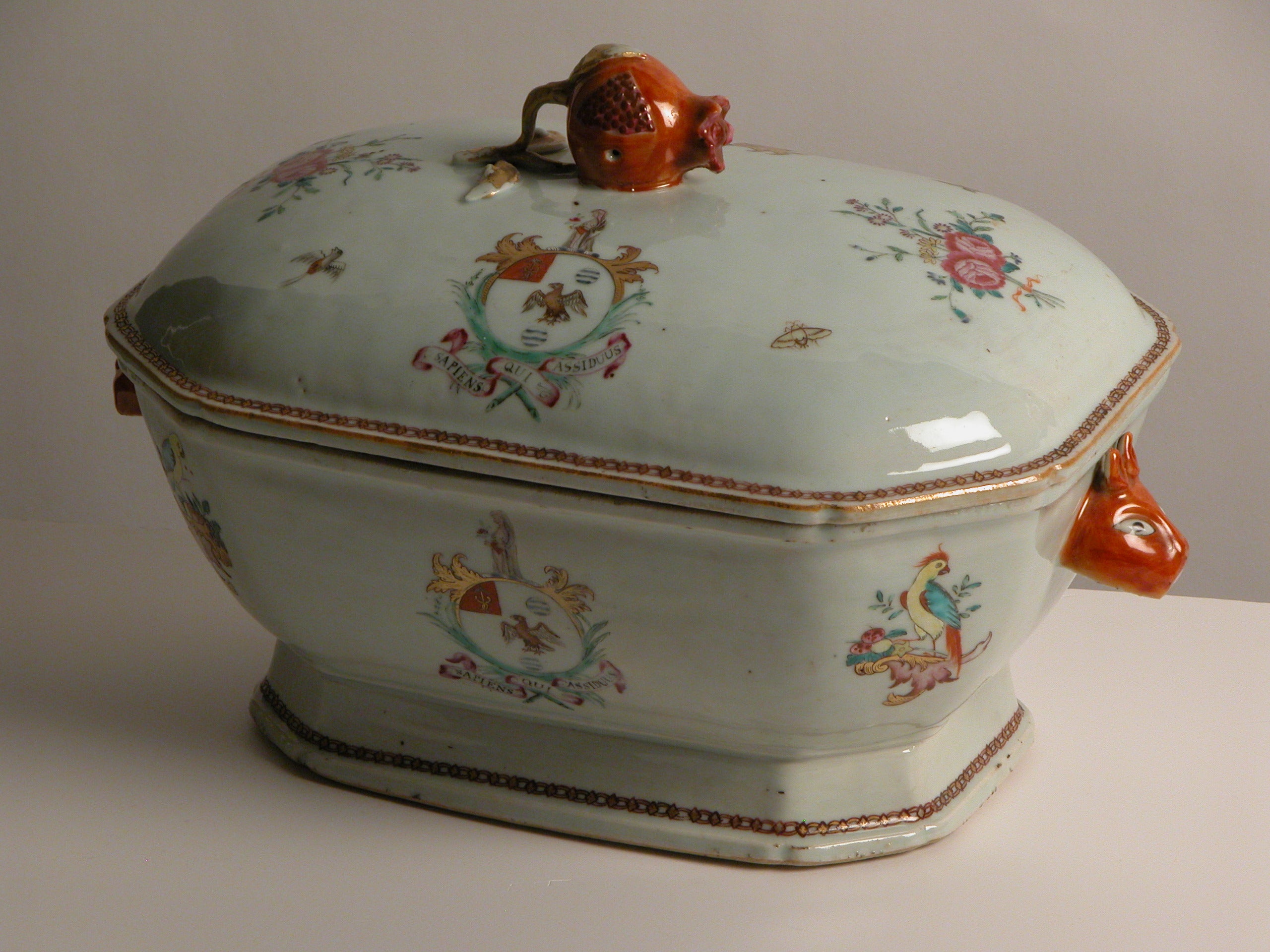 Tureen cover in famille rose enamels with the arms of Sykes of Basildon Park. Motif of two pink roses tied with a red ribbon surrounded by butterflies and birds. Edge of cover gilded.