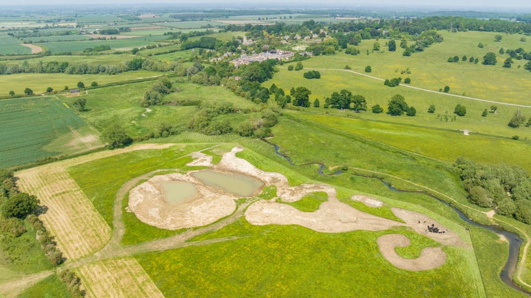 An aerial view of the green English countryside with fields, trees and newly created dry ponds
