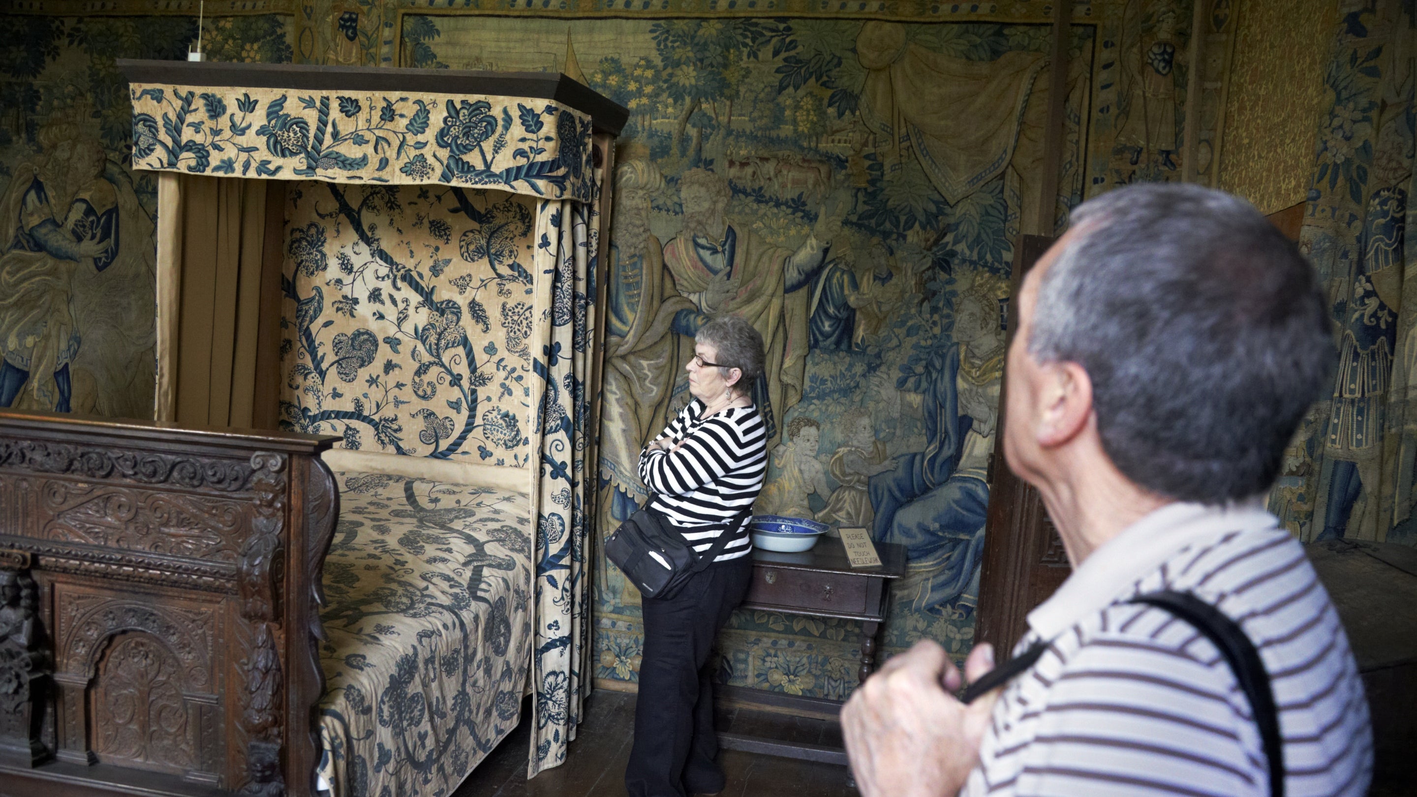 Visitors looking at the tapestries and bed hangings in the Fettiplace Room at Chastleton