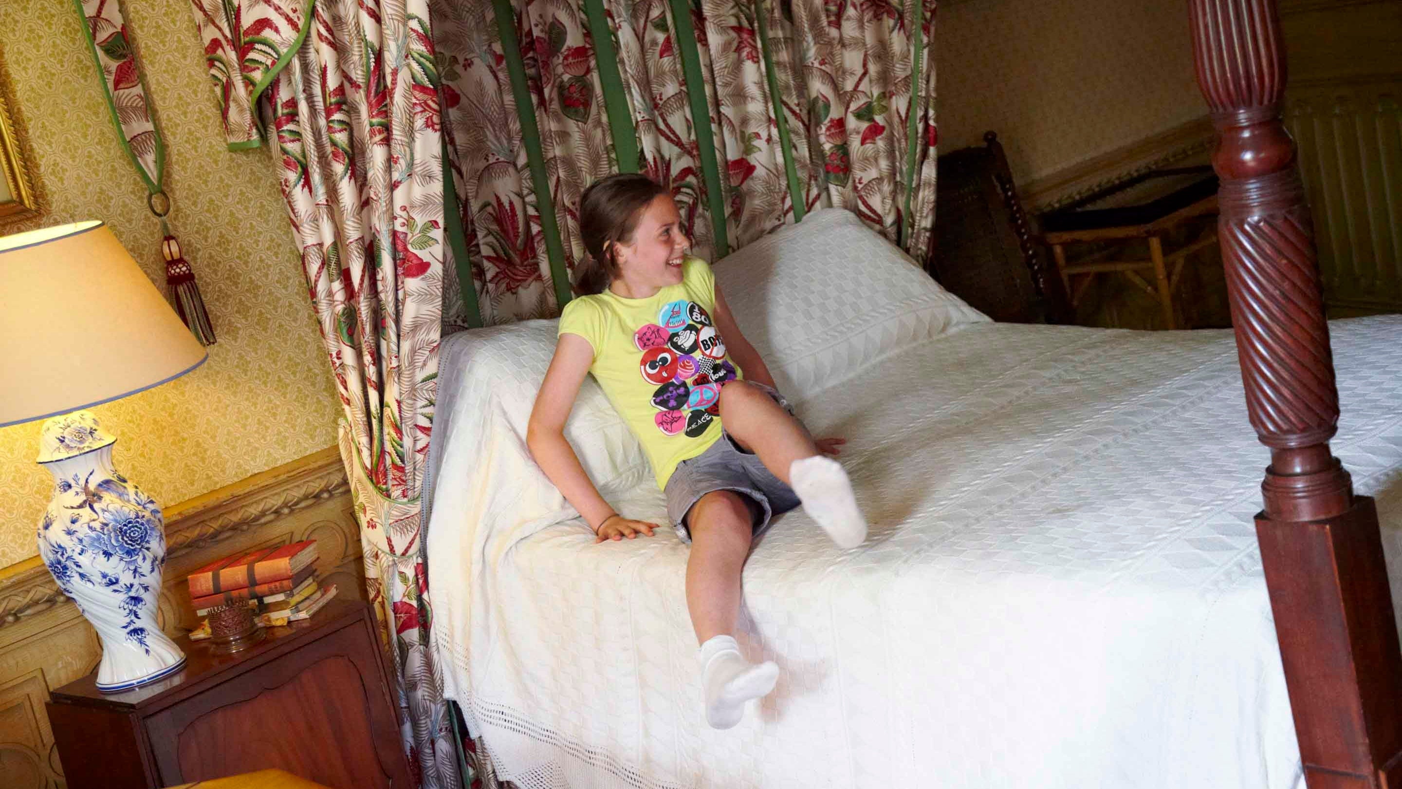 A child on Florence Nightingale’s wooden four poster bed at Claydon, Buckinghamshire
