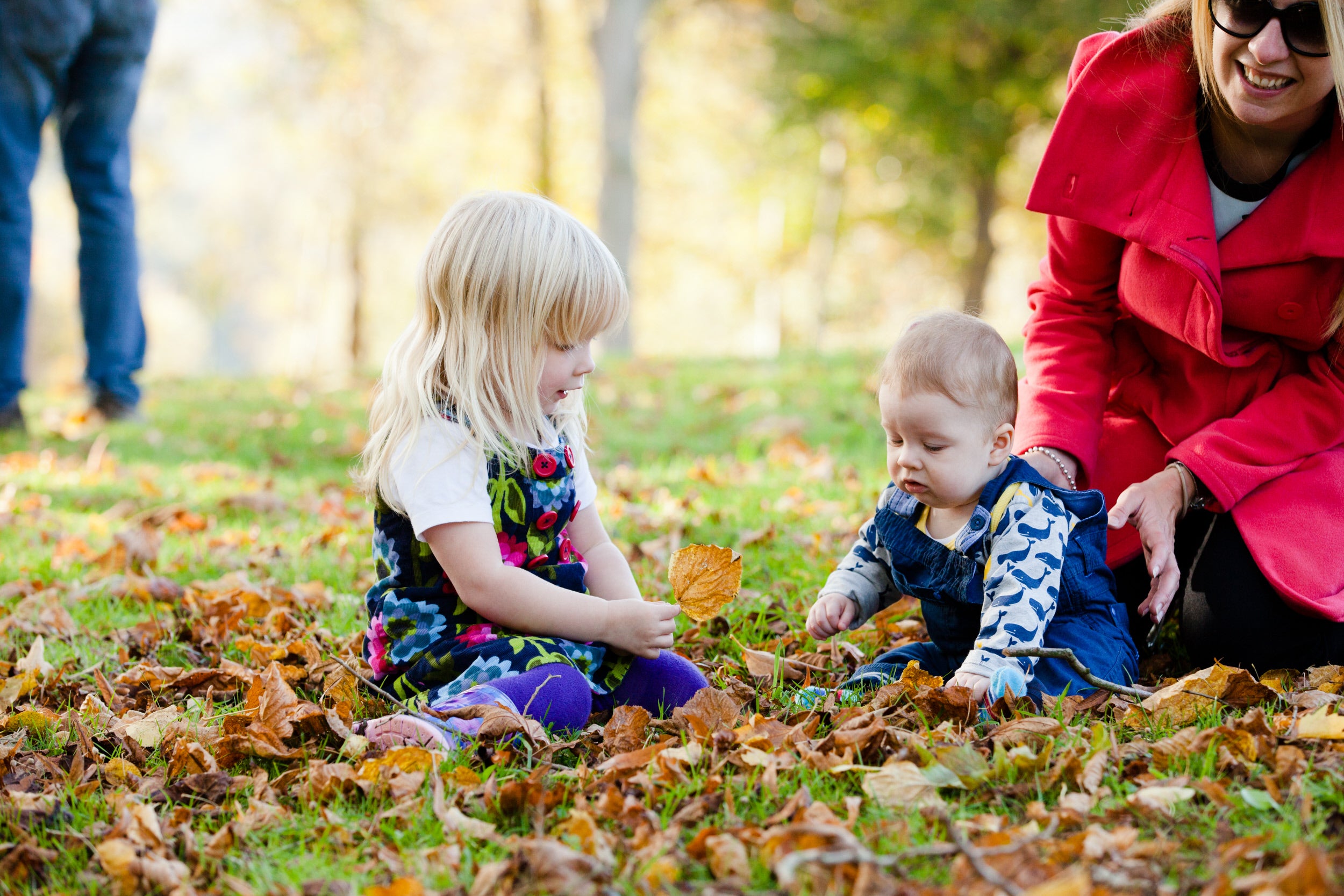 Two girls playing with autumn leaves in the gardens at Cliveden, Buckinghamshire.