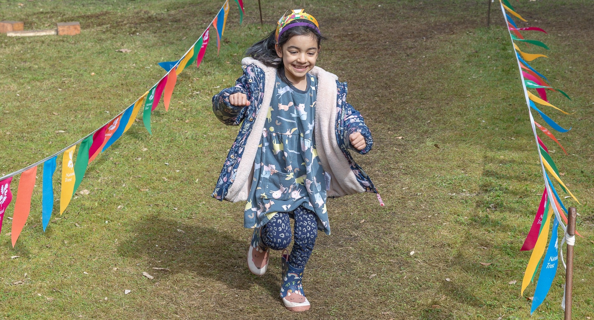 Girl with blue print dress and leggings enjoying the obstacle course in Ilex Grove at Cliveden, Buckinghamshire.