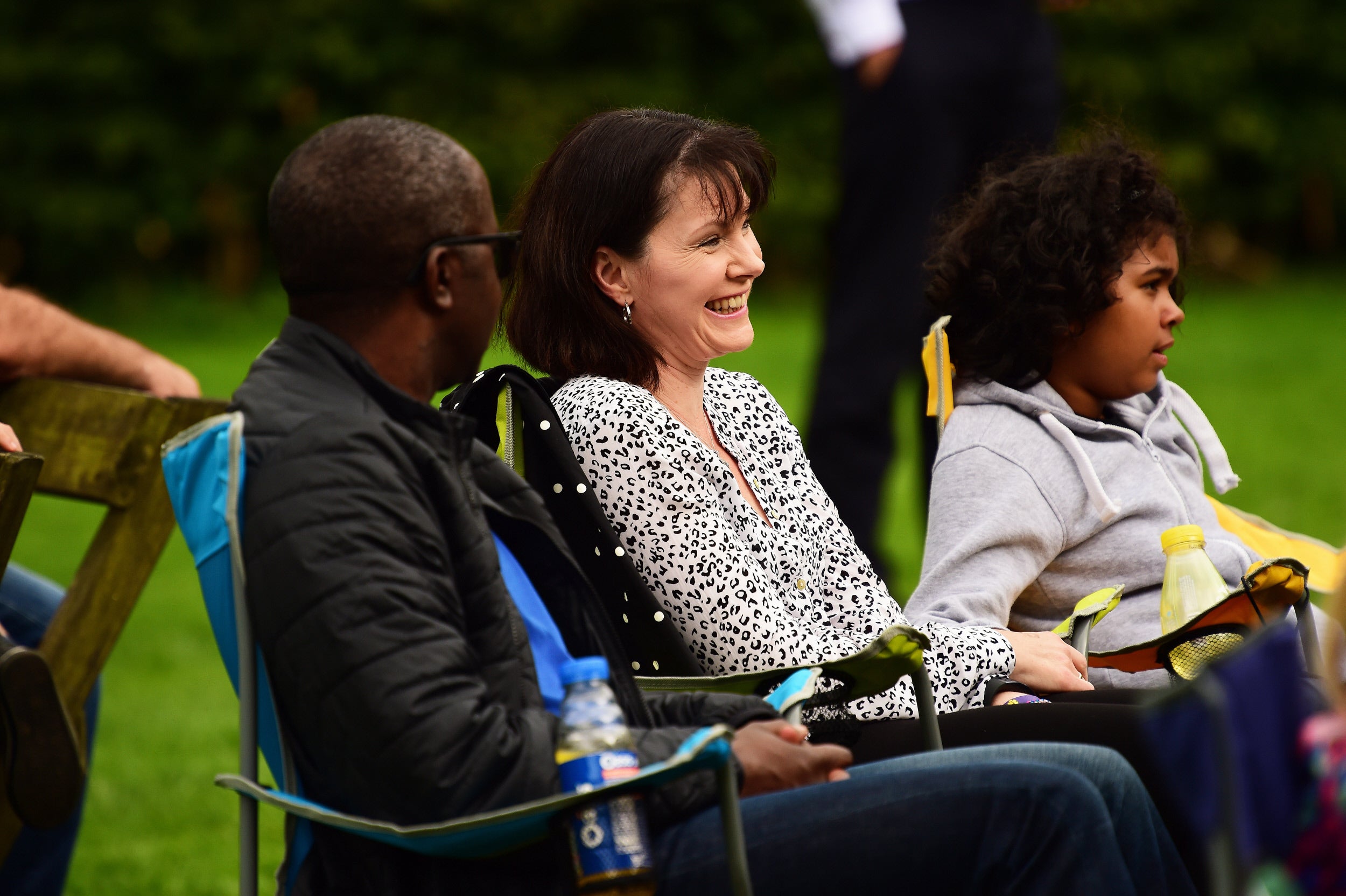 A family of three sitting in camping chairs enjoying a live performance at Cliveden, Buckinghamshire