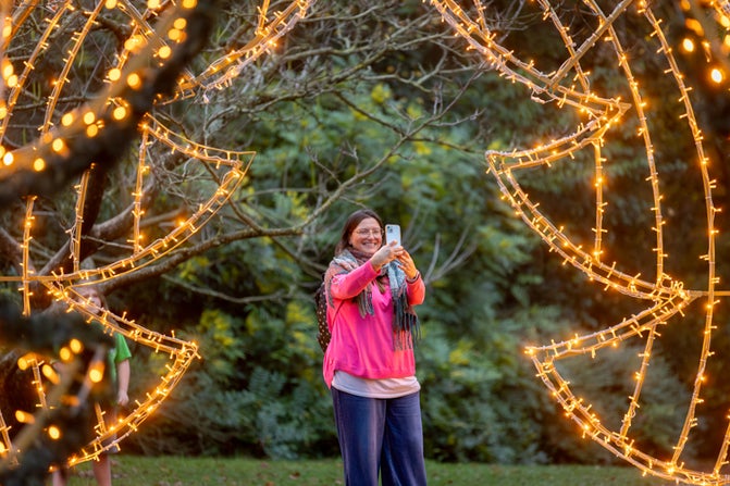 Visitor admiring the lit arch in the Water Garden