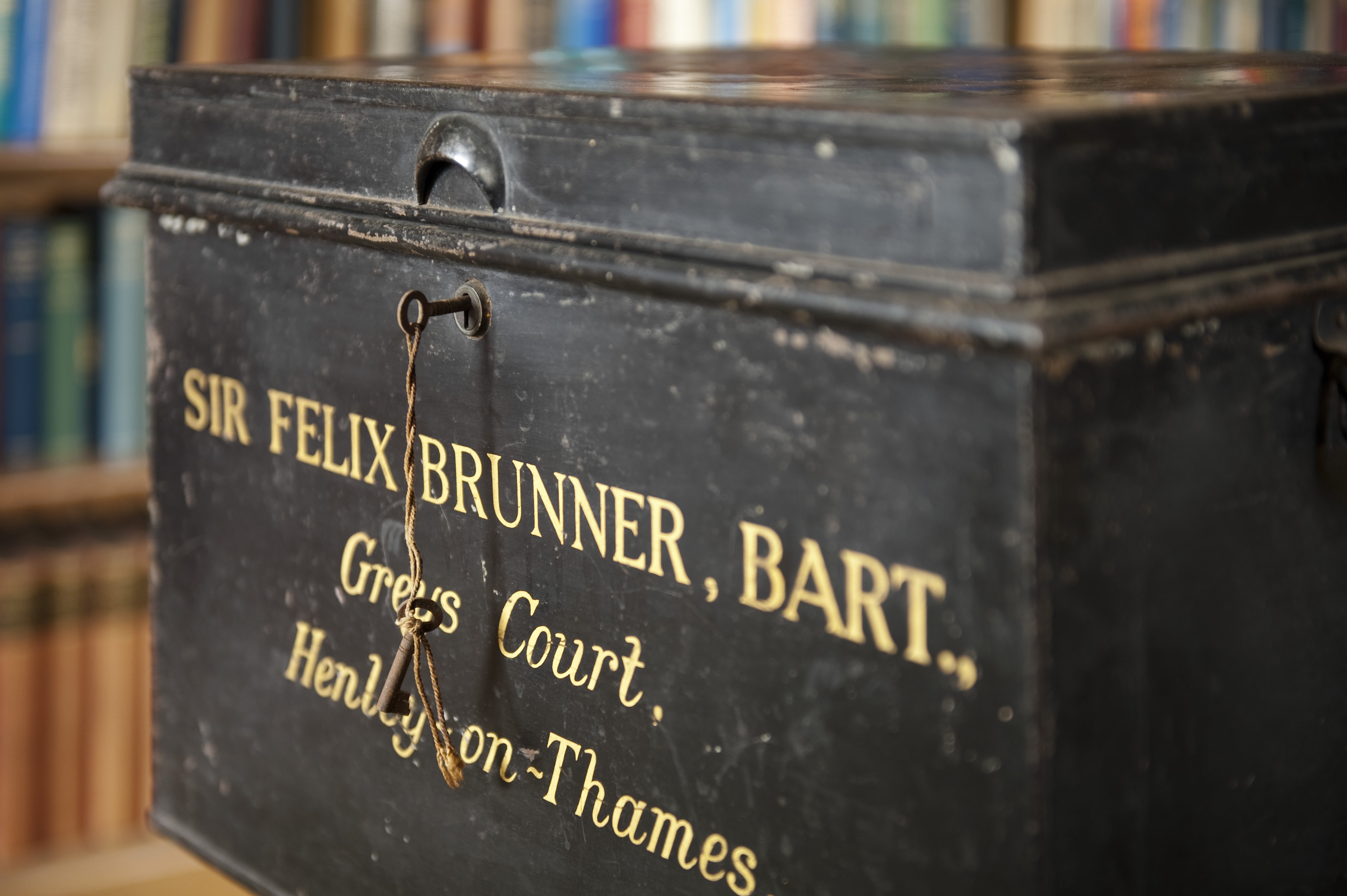 Metal box belonging to Sir Felix Brunner, in the Library at Greys Court, Oxfordshire. An up close image of a black metal box with 'Sir Felix Brunner bart. Greys Court Henley on Thames' in gold lettering.