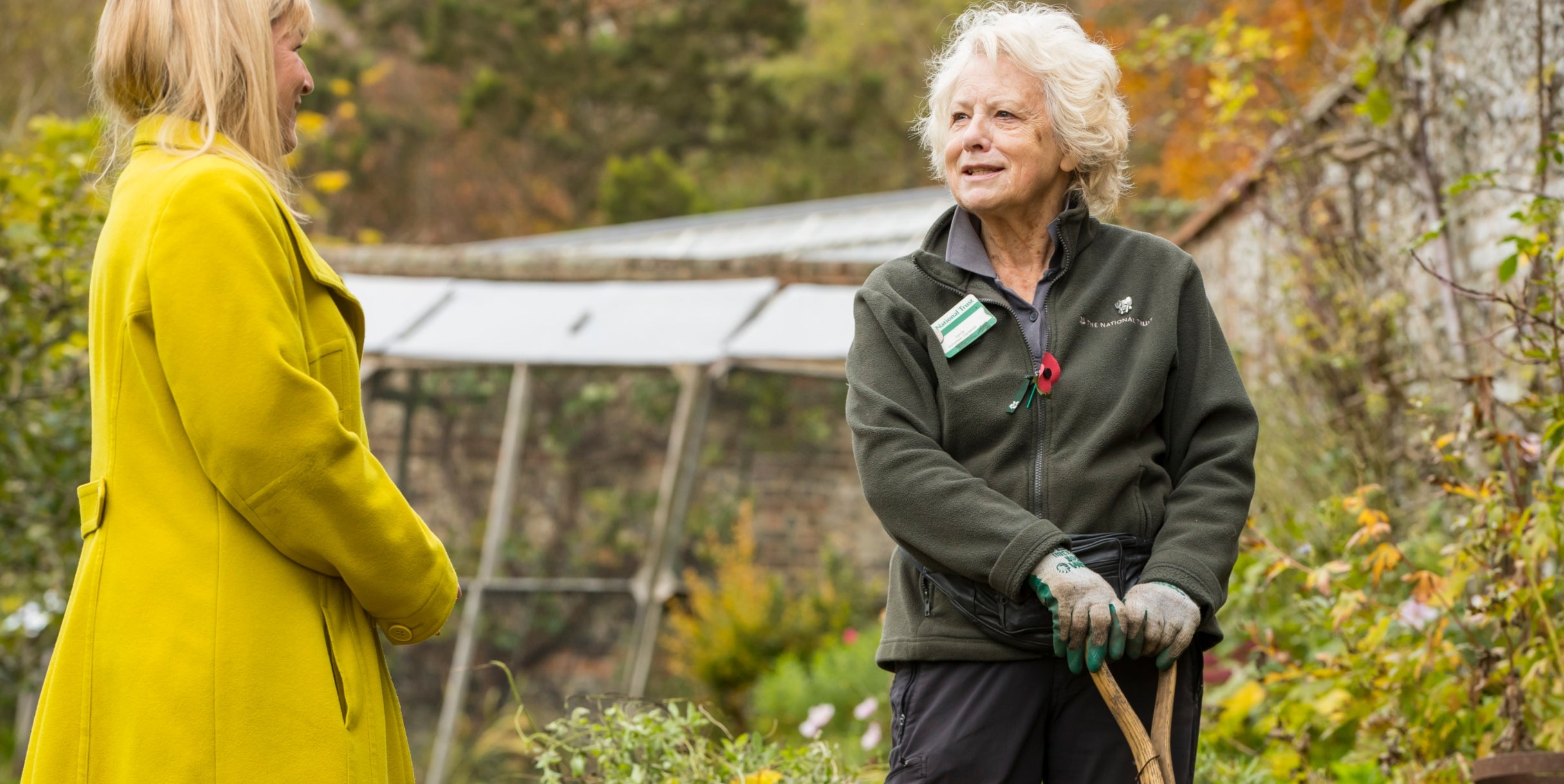 Garden volunteer speaking with a visitor in the Walled Garden at Hughenden.