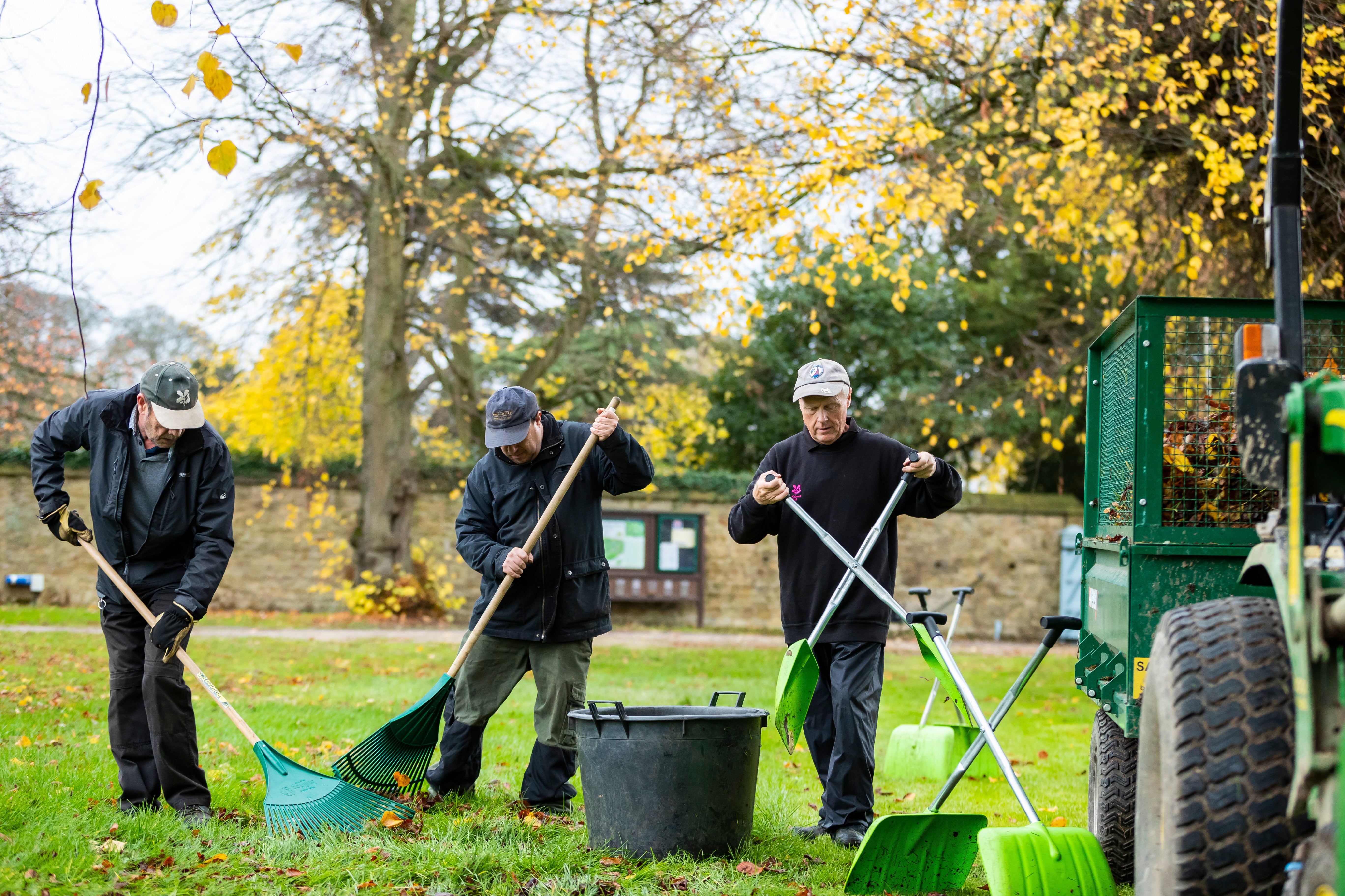 Gardeners clearing away autumn leaves