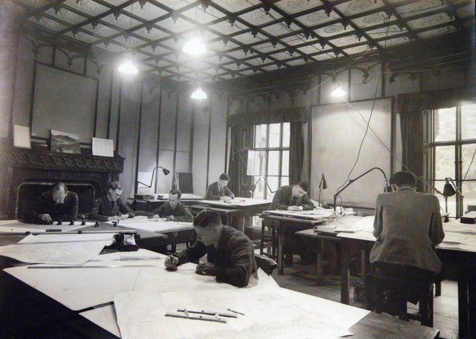 Black and white photograph of mapmakers at desks in the Dining Room of Hughenden Manor