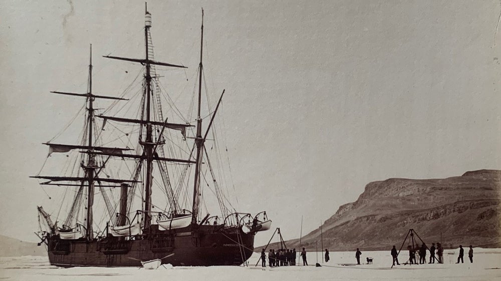 Historic Arctic expedition team standing beside a wooden boat