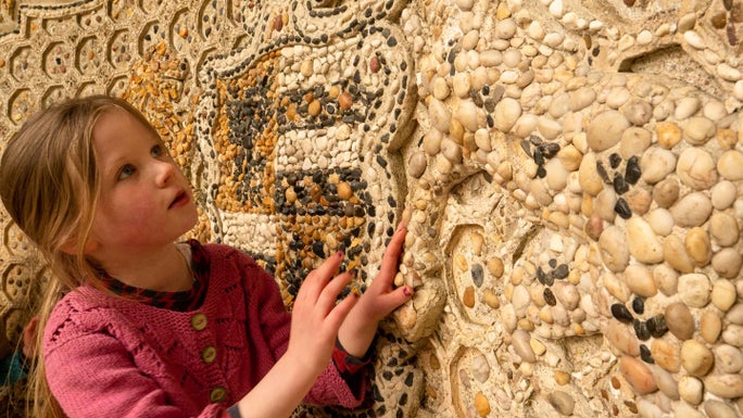 A girl looks at the detail of the Pebble Alcove at Stowe, Buckinghamshire.