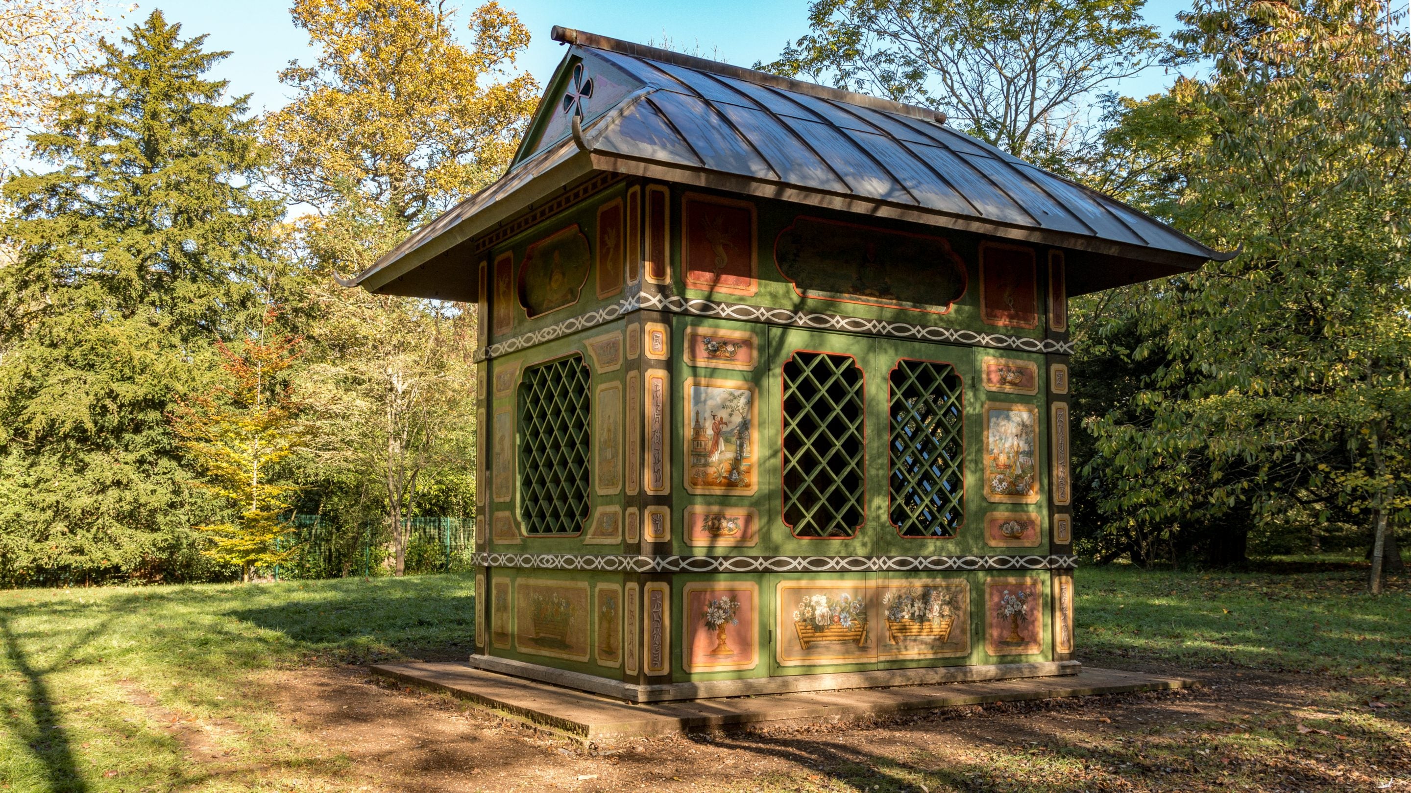 A small timber building highly decorated in green, red and gold with an oriental design