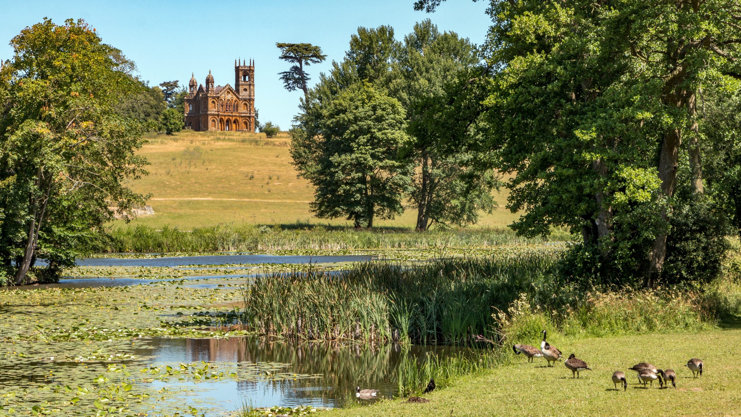 A view of the Gothic Temple at Stowe in Buckinghamshire in the distance across the lake and landscape garden
