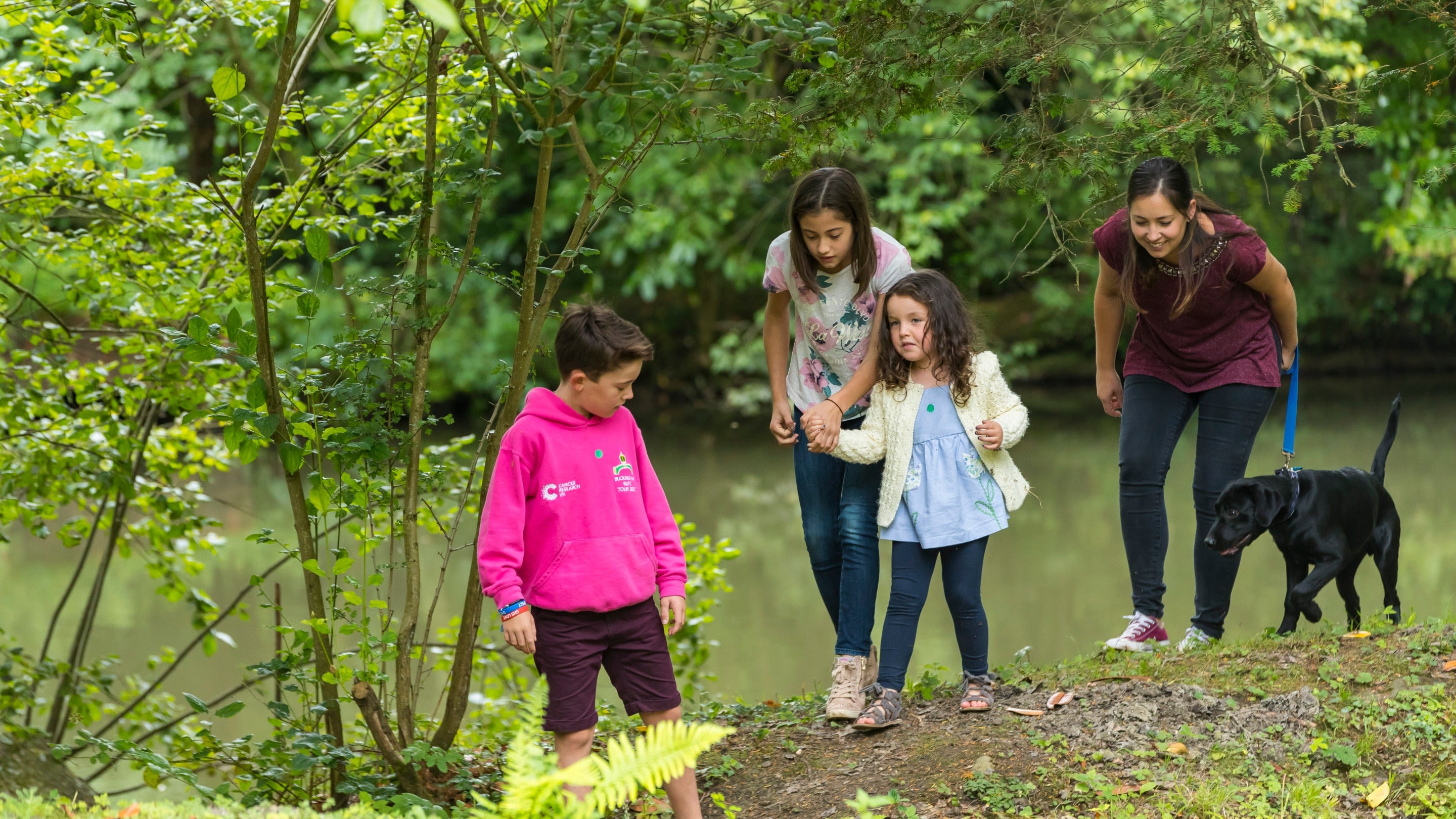 A family walk with their dog beside the water at Stowe, Buckinghamshire