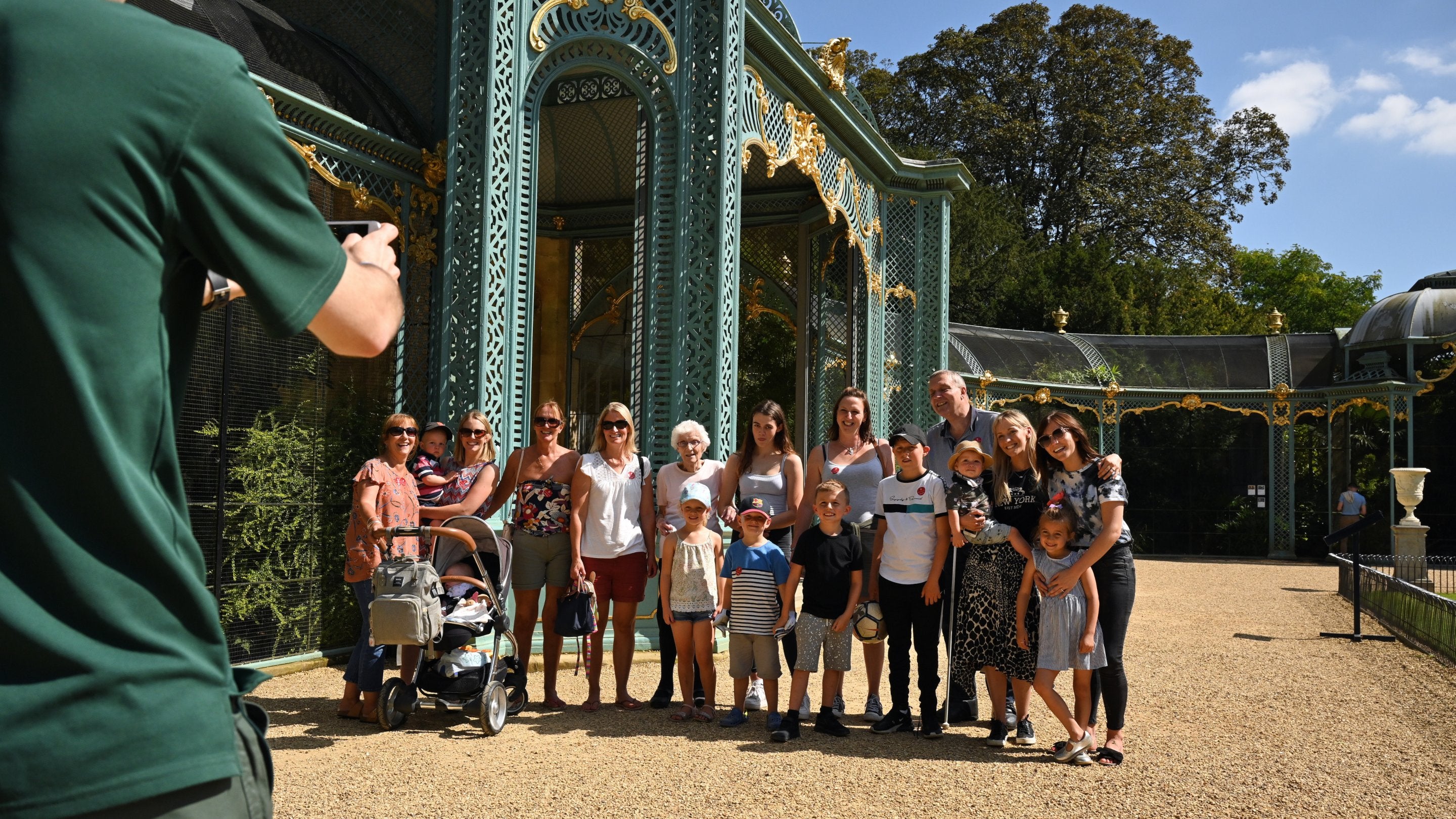 A man takes a photo of a group of visitors by the Aviary at Waddesdon Manor, Buckinghamshire