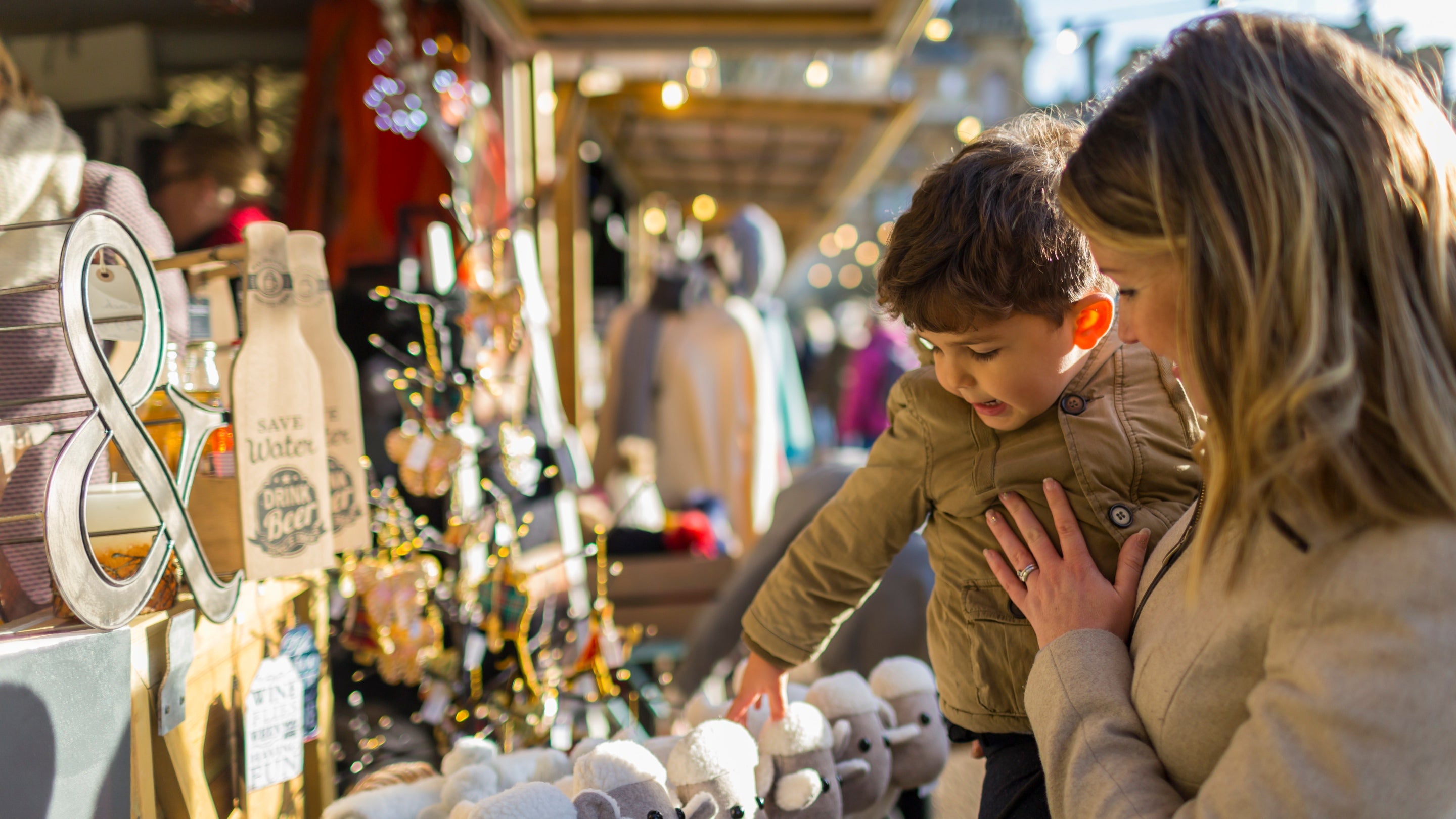 A woman carrying a little boy as they look at a market stall