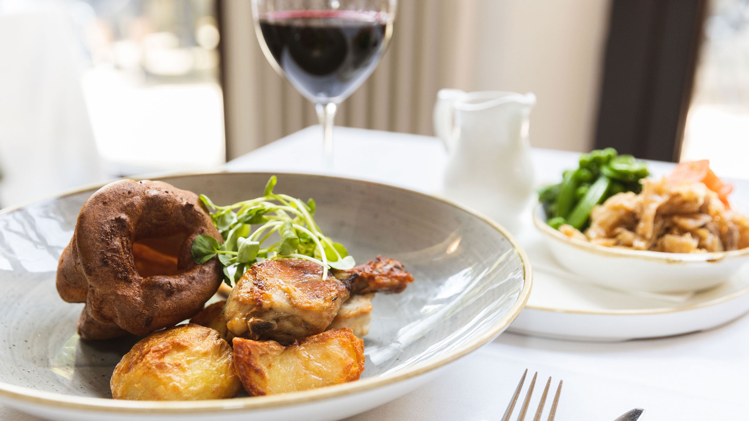 Sunday roast on grey plate with glass red wine in background