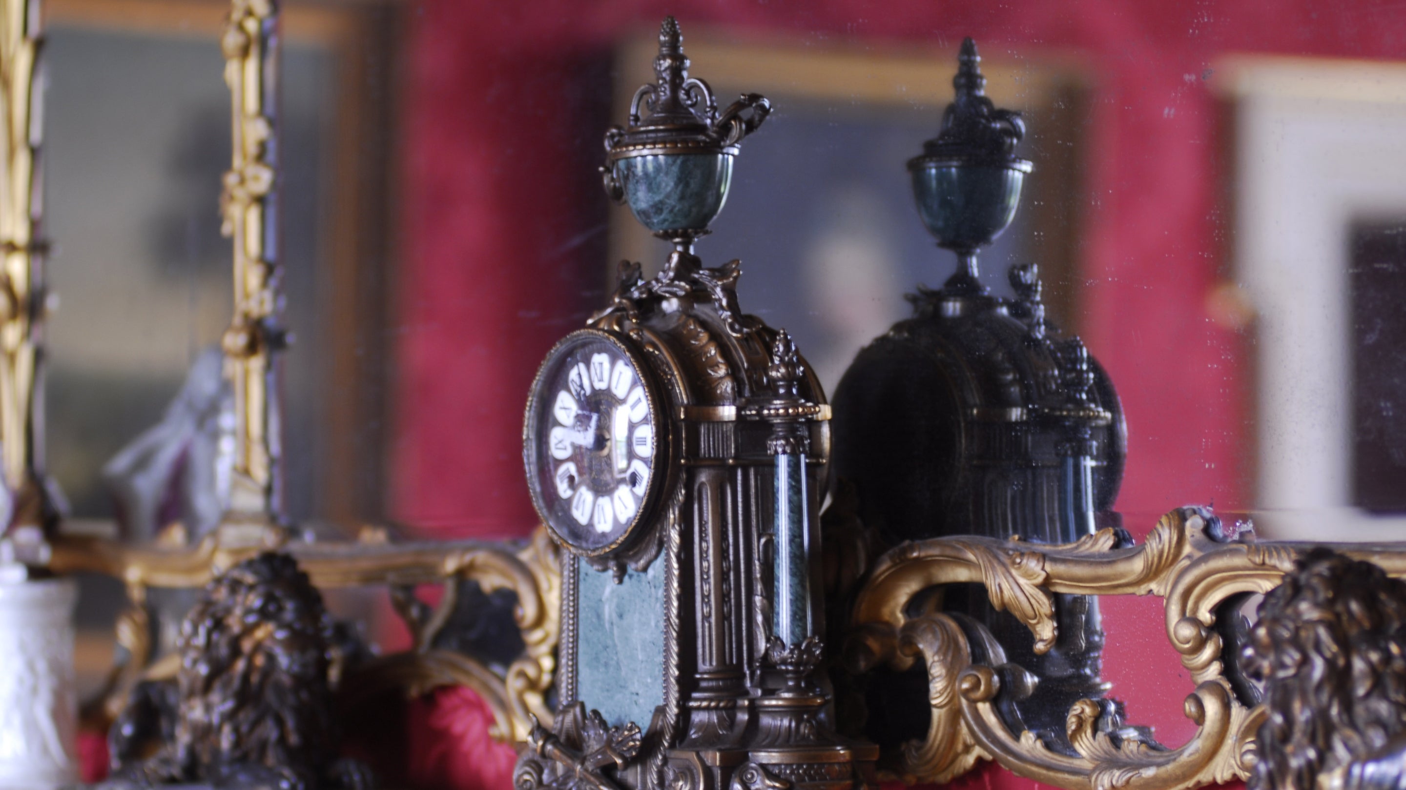 An ornate clock displayed on a mantelpiece at West Wycombe Park