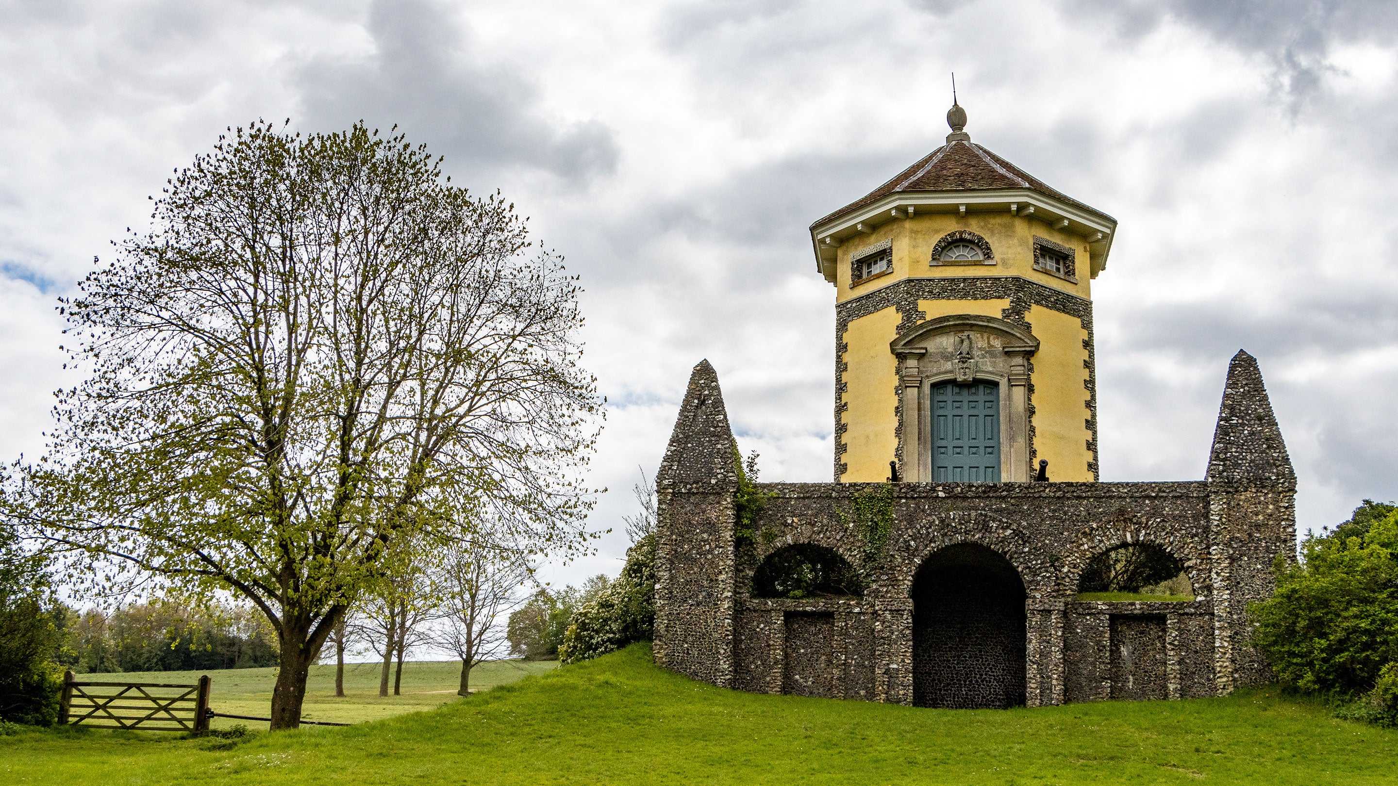A temple designed in the classical style, a hexagonal, stone built and plastered temple sits atop a bare stone base with an arched opening