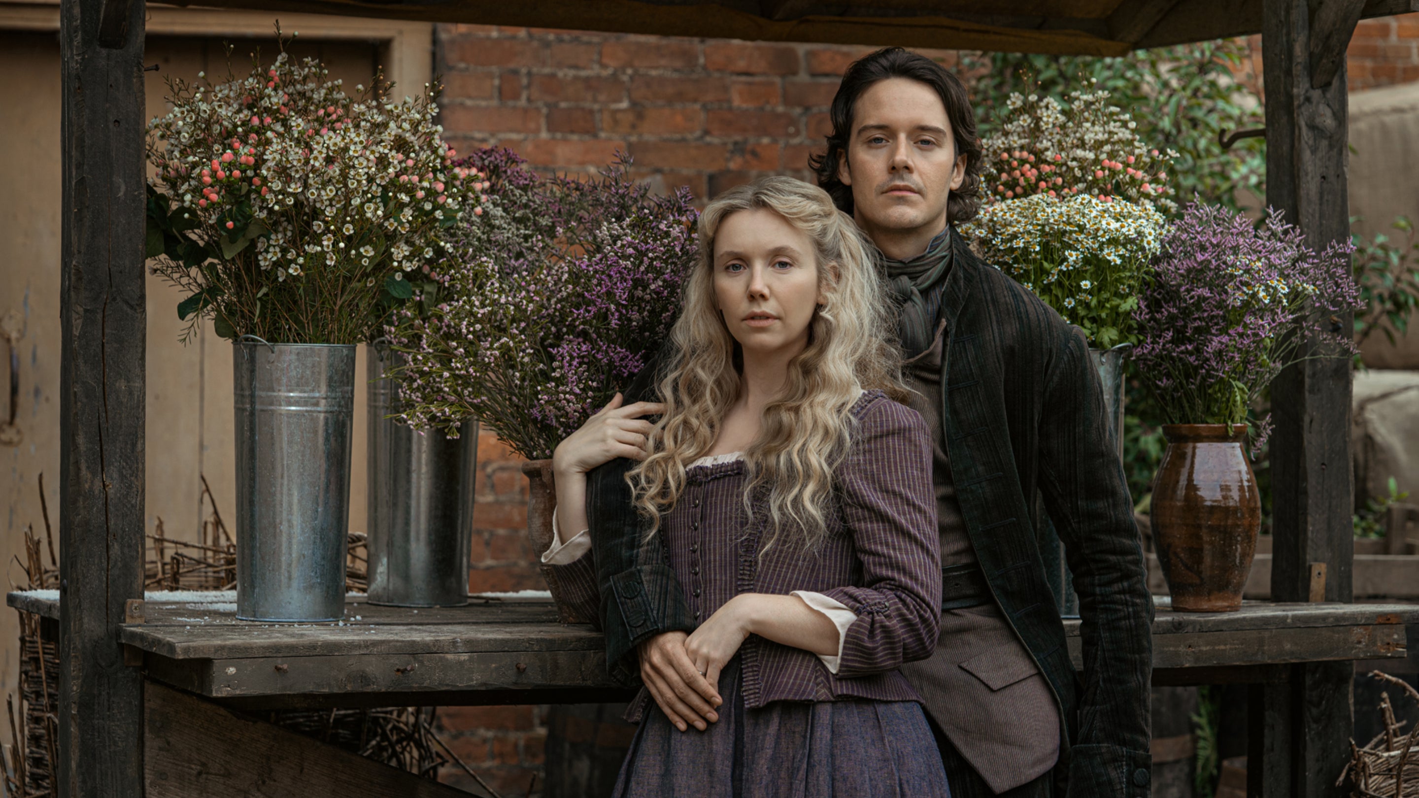 A man and a woman stand in front of a flower cart