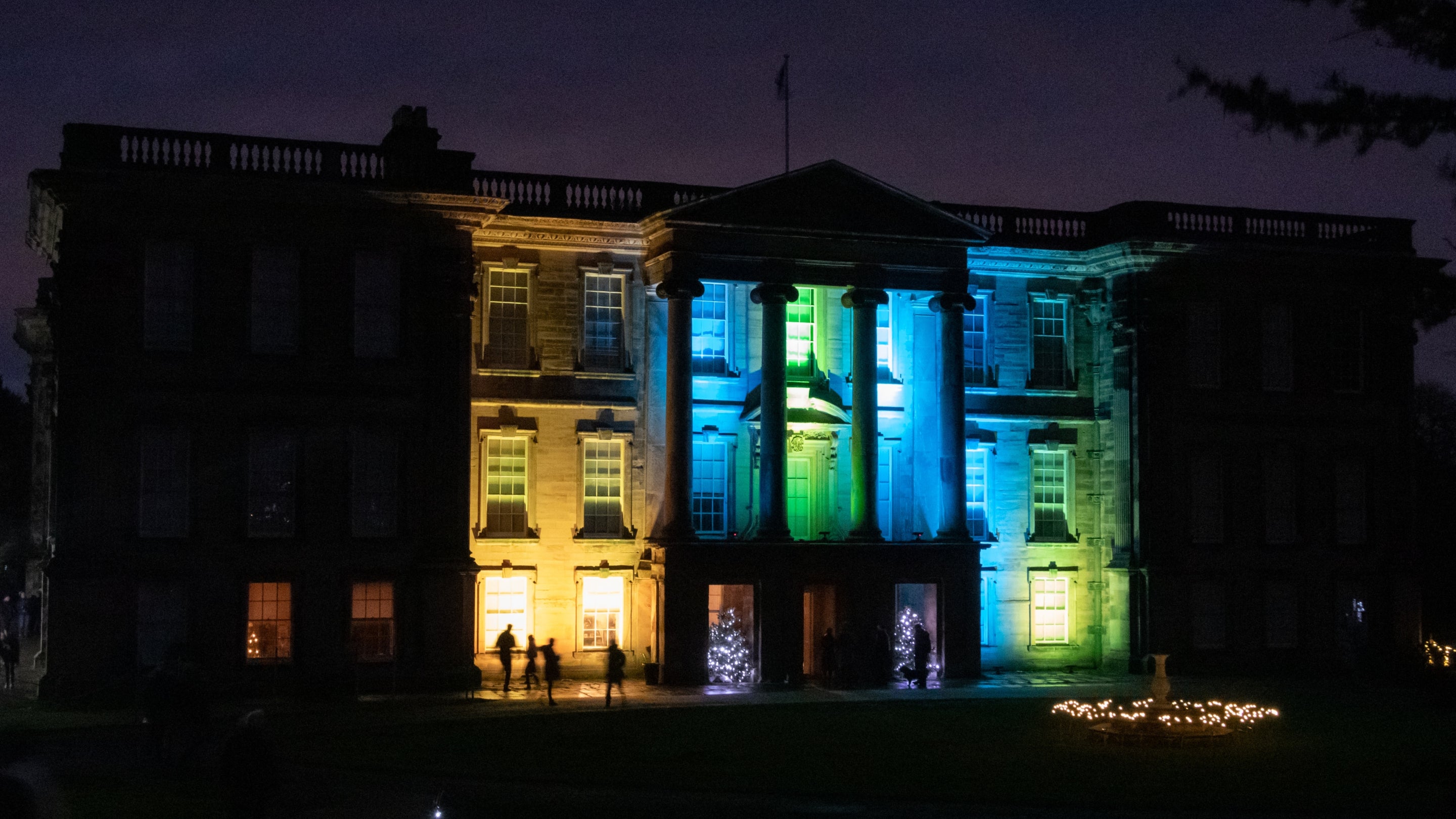 Christmas lights illuminate the front of Calke Abbey on a dark winters evening.