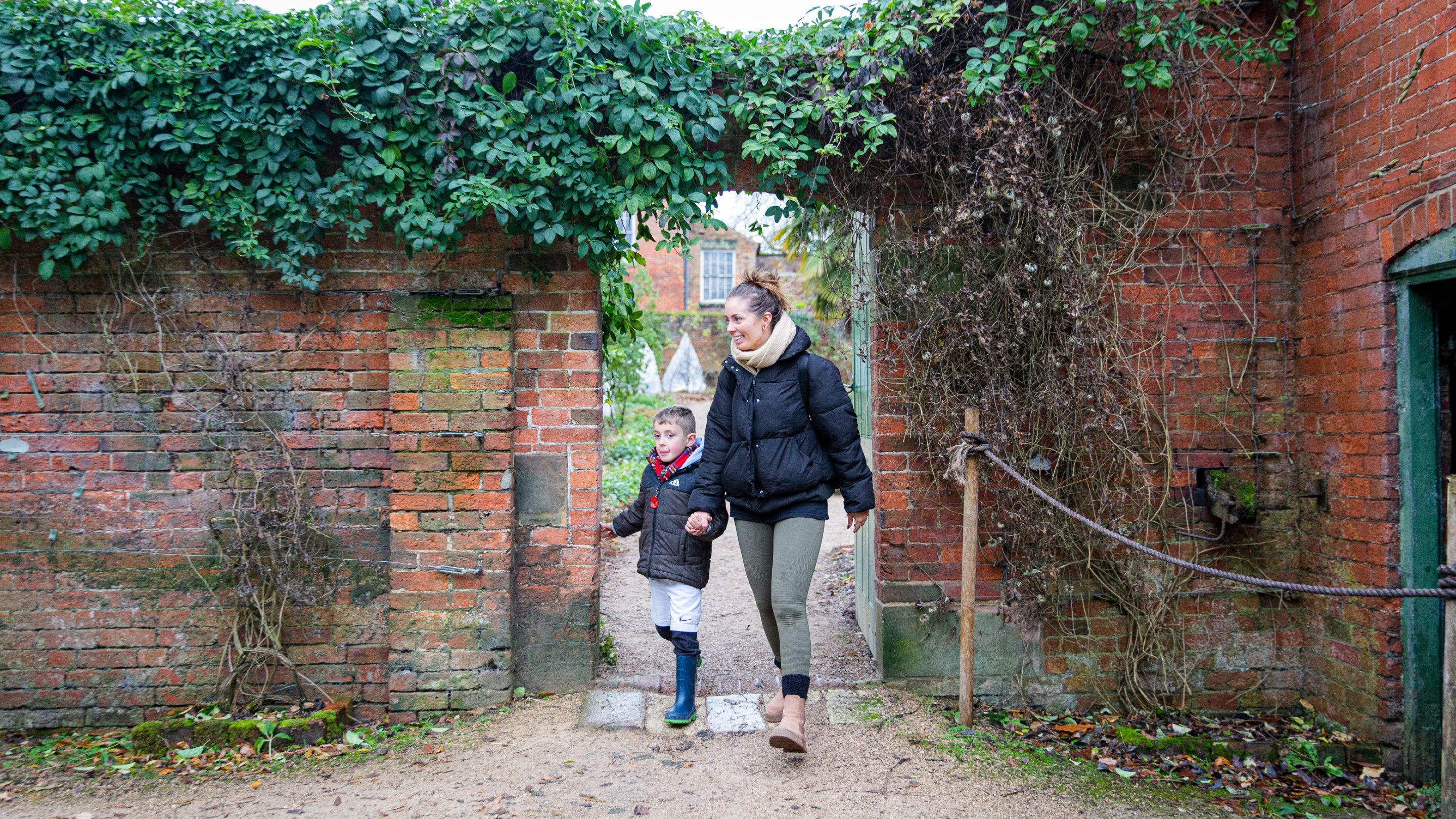 A mum and son walking through a brick archway