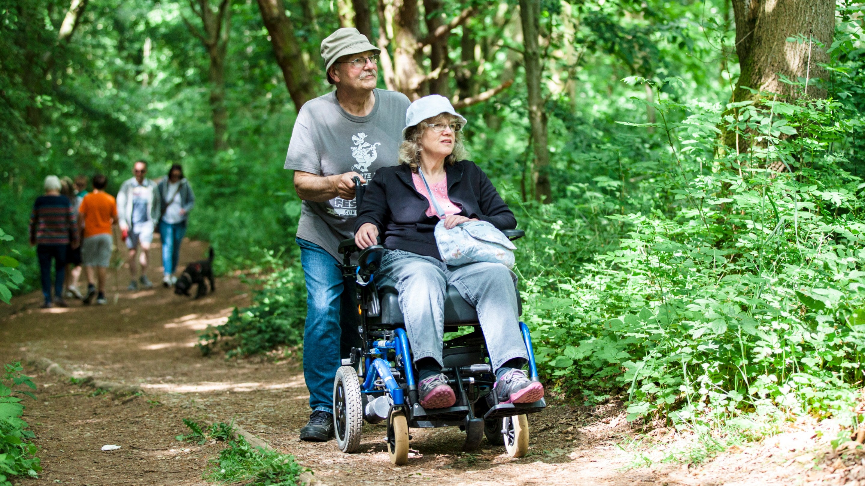 Visitors exploring the accessible footpath at Foremark, Derbyshire in woodland surrounded by trees